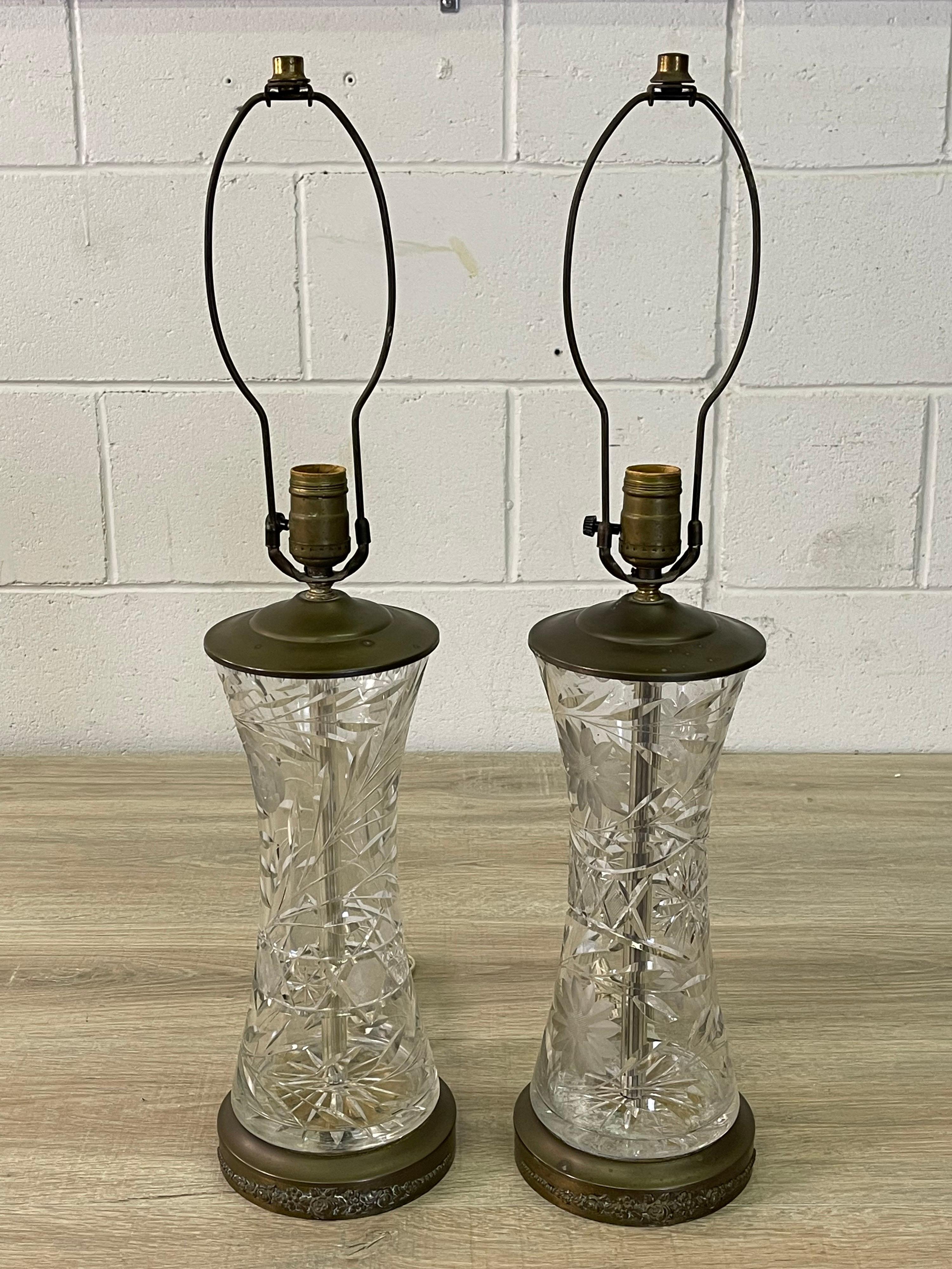 Vintage 1950s pair of floral glass table lamps with brass accents. The top and bottom of the lamps are brass while the center is all glass with a floral design. Wired for the US and in working condition. The brass base has a rose floral design.