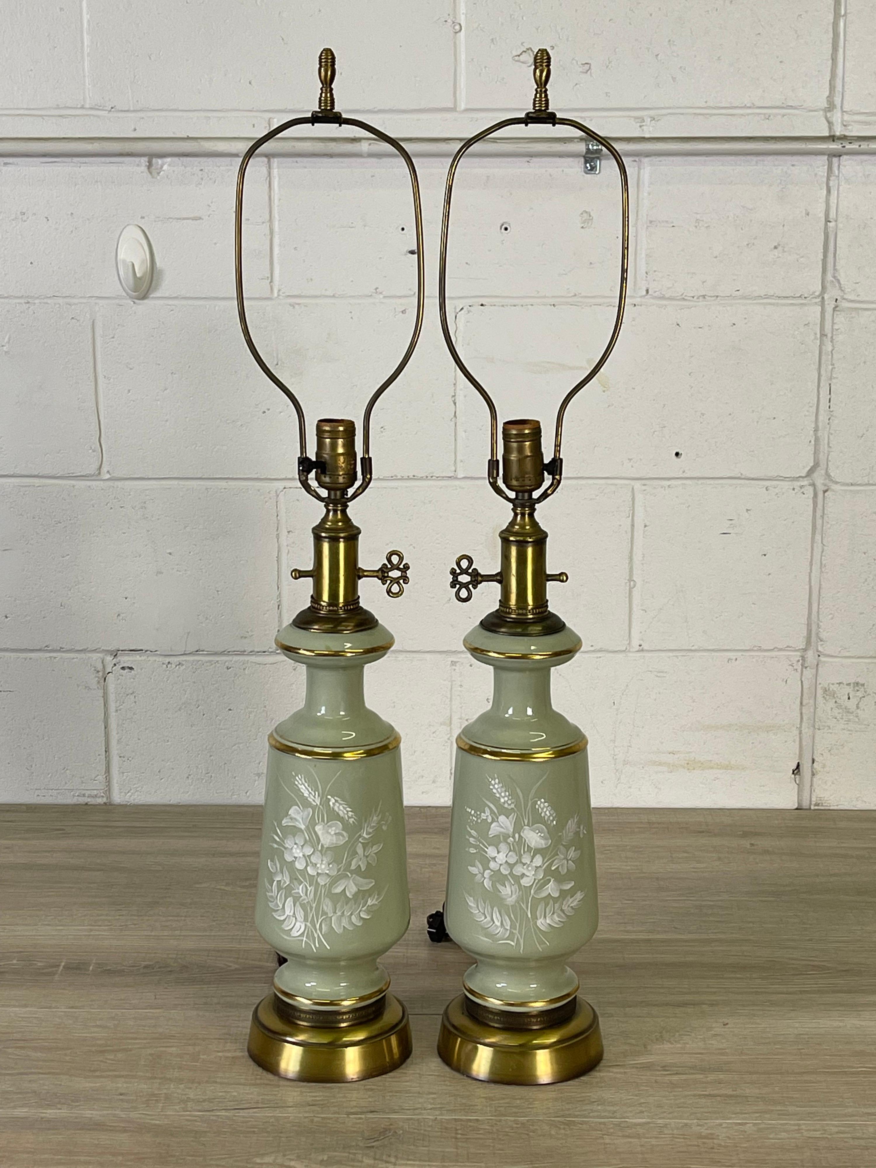 Vintage 1950s pair of glass handpainted floral table lamps with brushed brass accents. Painted on both the front and the back of the lamps. Wired for the US and in working condition. Uses a standed 100 watt bulb. Also can use a 3-way bulb. Socket,