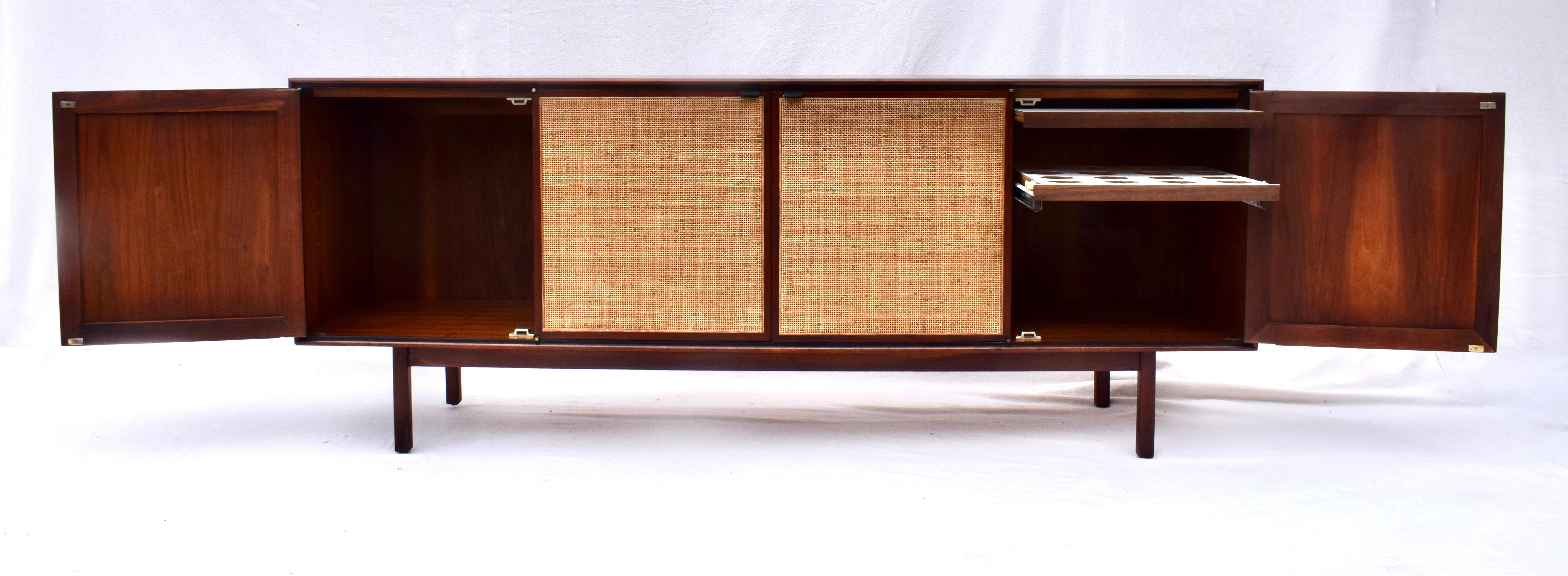 Scarcely seen early 1950's Florence Knoll walnut credenza. So many marvelous features include four caned doors with leather pulls, two generously sized drawers, side bar with spacious cabinetry & work surface boasting all original hand rubbed