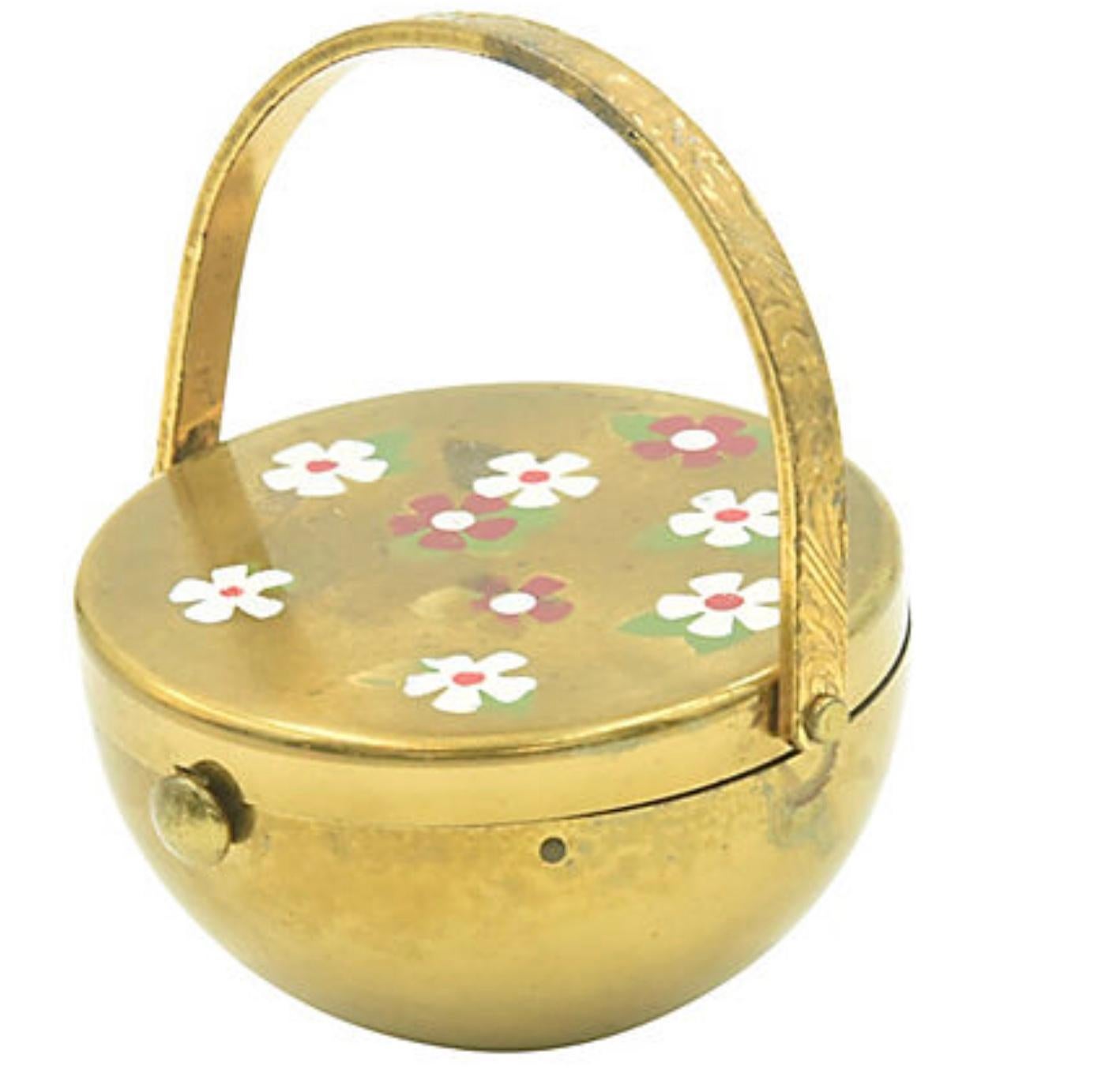 Mid 20th century compact in the shape of a flower basket. The top is covered with red and white daisy-like flowers. The handle has pretty details and is moveable. Inside, the screen is clean and unused. Unsigned; attributed to Kigu. Tarnished, paint