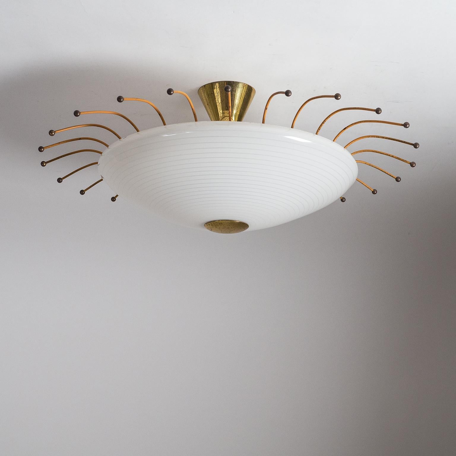 Charming midcentury ceiling light, circa 1950. A glass disc, frosted on the inside, with concentric white enameled circles is held by a brass hardware. Surrounding the glass is an array of wires lacquered in a subdued 'rusty orange' with brass