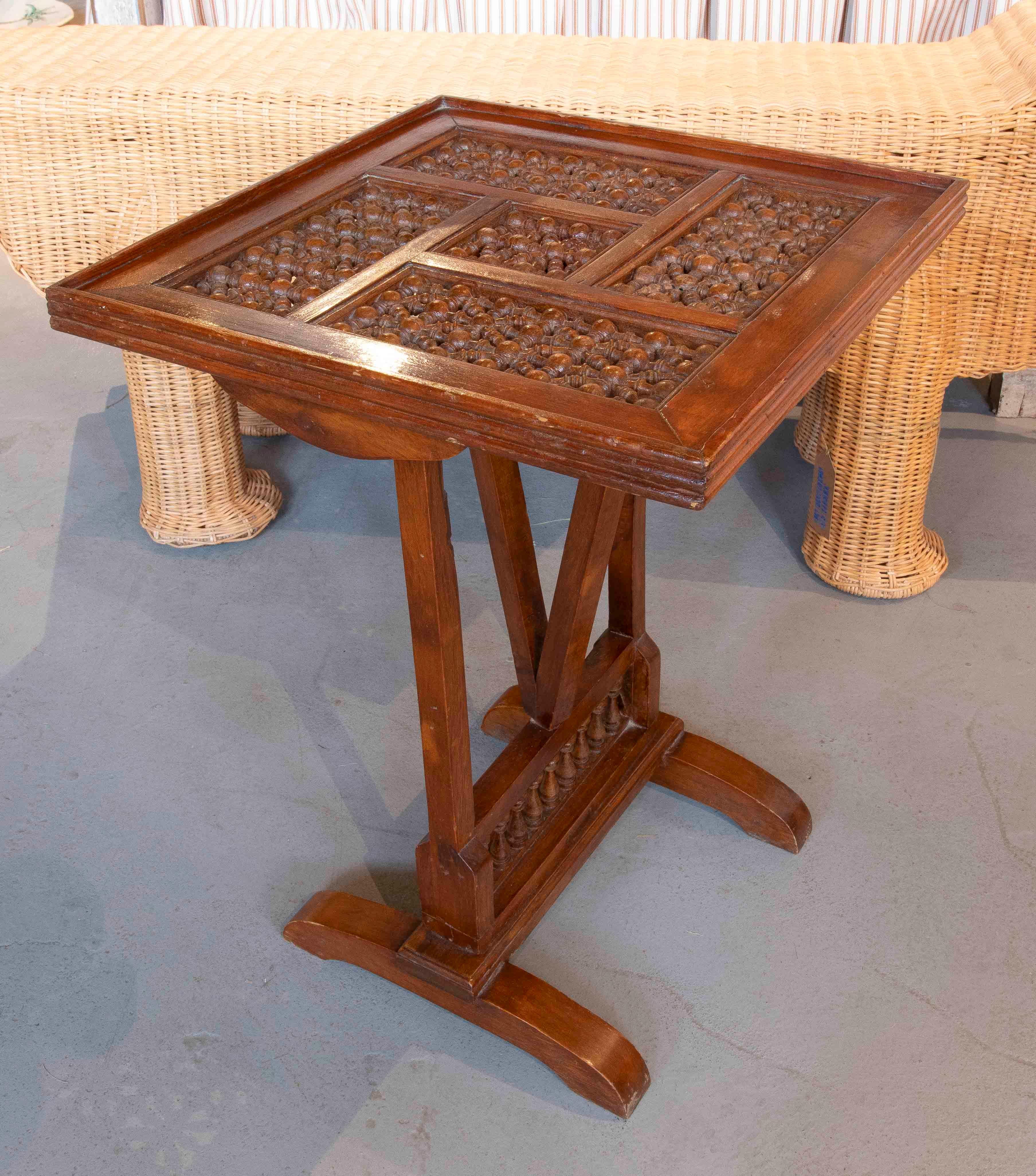 Elegant solid wood side table with a folding top and exquisite hand-carved latticework. Its surface features a geometric design formed by turned pieces that add depth and texture. The central leg, joined by decorative crossbars, provides excellent