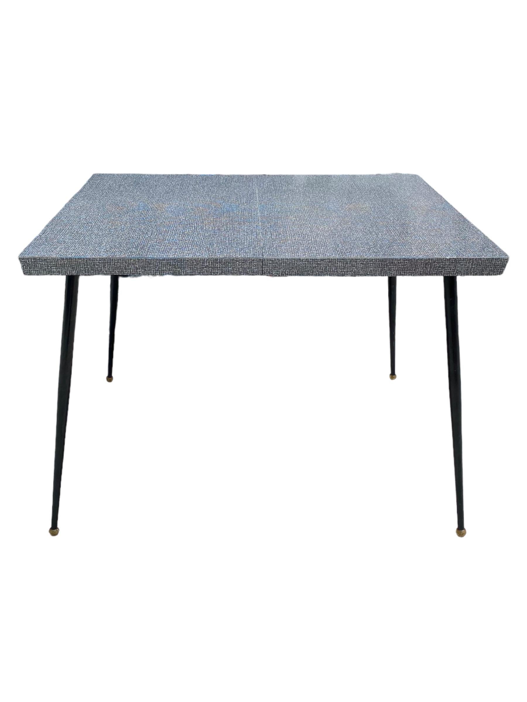 Excellent mid century vintage dining table with graphic Formica top and tapered atomic style legs. The table is just shy of 40 inches long and has an 8 inche leaf insert. No chips to laminate. Ball feet on bottom of legs. Autherhfic retro table with