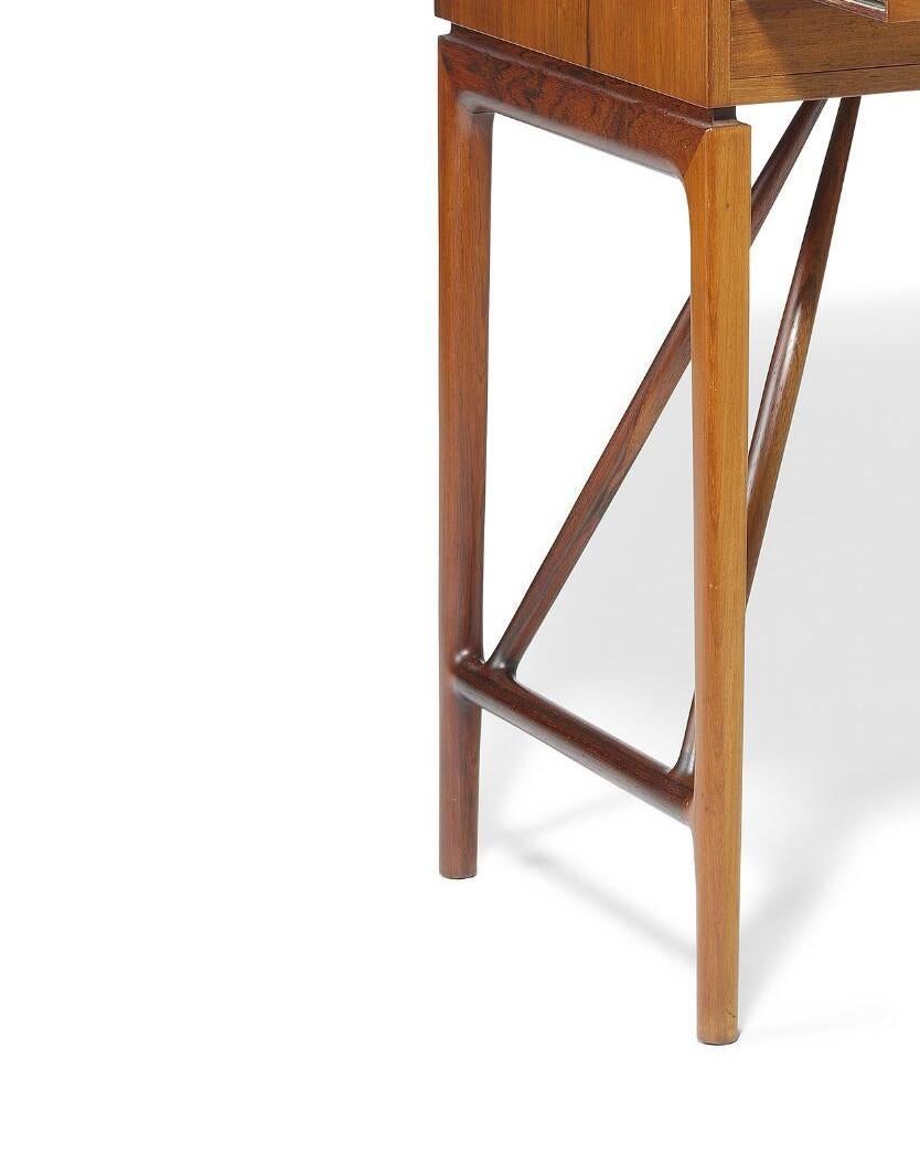 1950s Freestanding  Bureau de dame, cadre avec étirements obliques. Façade avec deux tiroirs, au-dessus d'une feuille d'écriture extractible. Dessus avec trois tiroirs, espace de rangement et deux armoires, chacune avec une étagère en verre