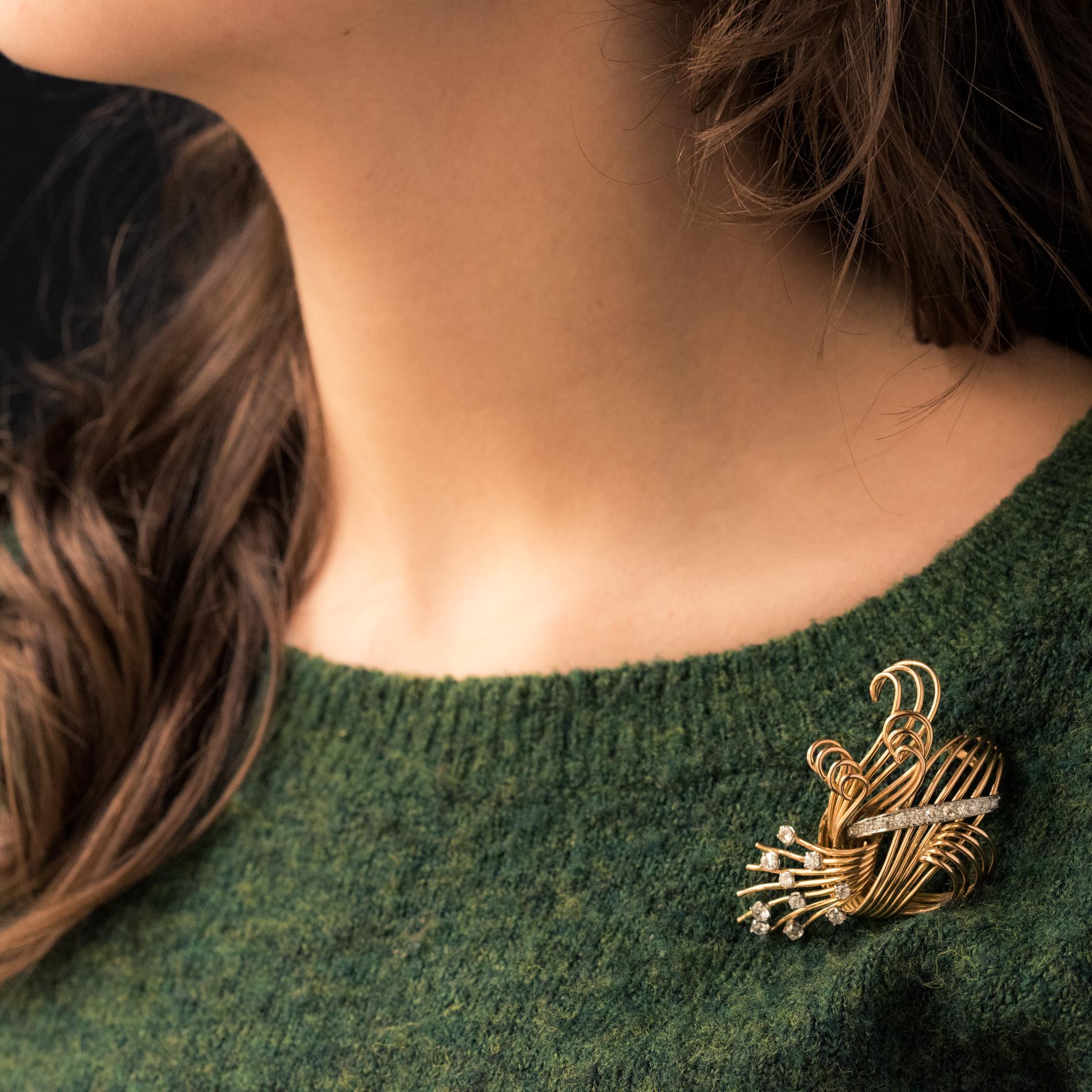 Spilla in oro giallo 18 carati, marchio di garanzia testa d'aquila e platino.
La montatura è composta da fili d'oro annodati a mo' di covone con una linea di diamanti incastonati su platino e diamanti taglio brillante con griffe sui fili d'oro. La