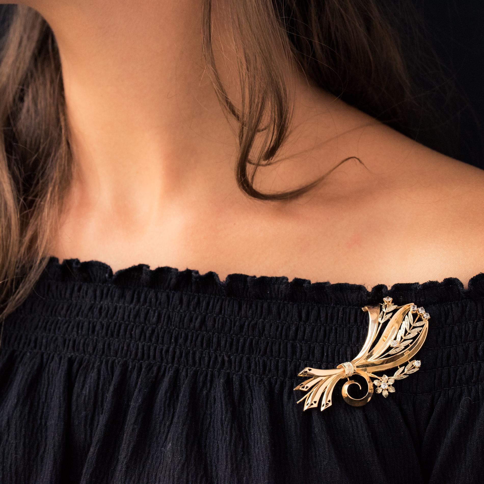 Brooch in 18 karat yellow gold with eagle's head hallmark.
Styling a bouquet of flowers, this retro brooch is set with claws of round aquamarines, and chiseled white gold motifs representing the leaves. The bouquet is held by a ribbon set with 3