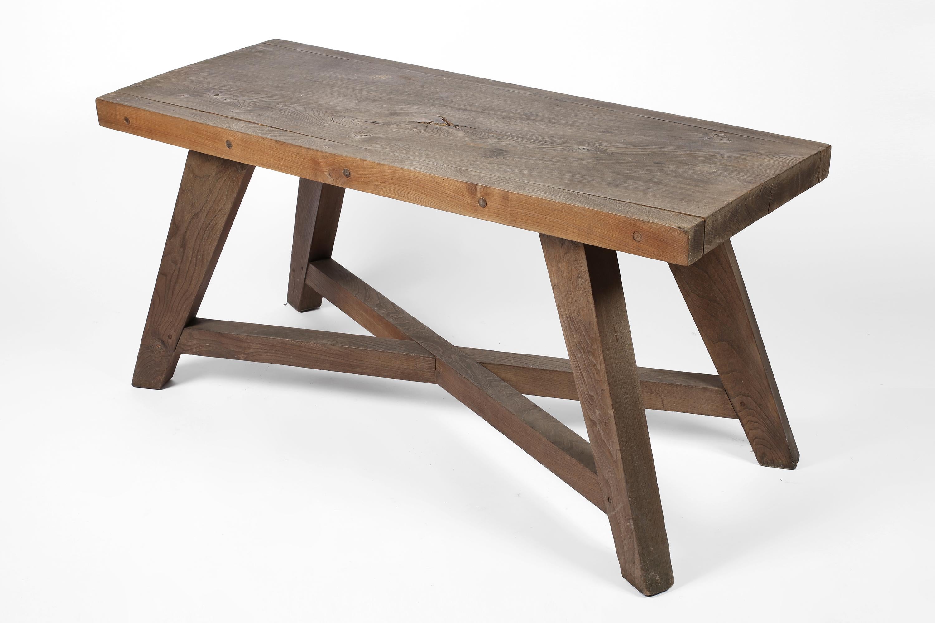 An architect made dining table constructed from solid elm, with compass legs, cross stretcher and a beautiful weathered grey patina. Would also serve as a desk/console table. French, c. 1950.