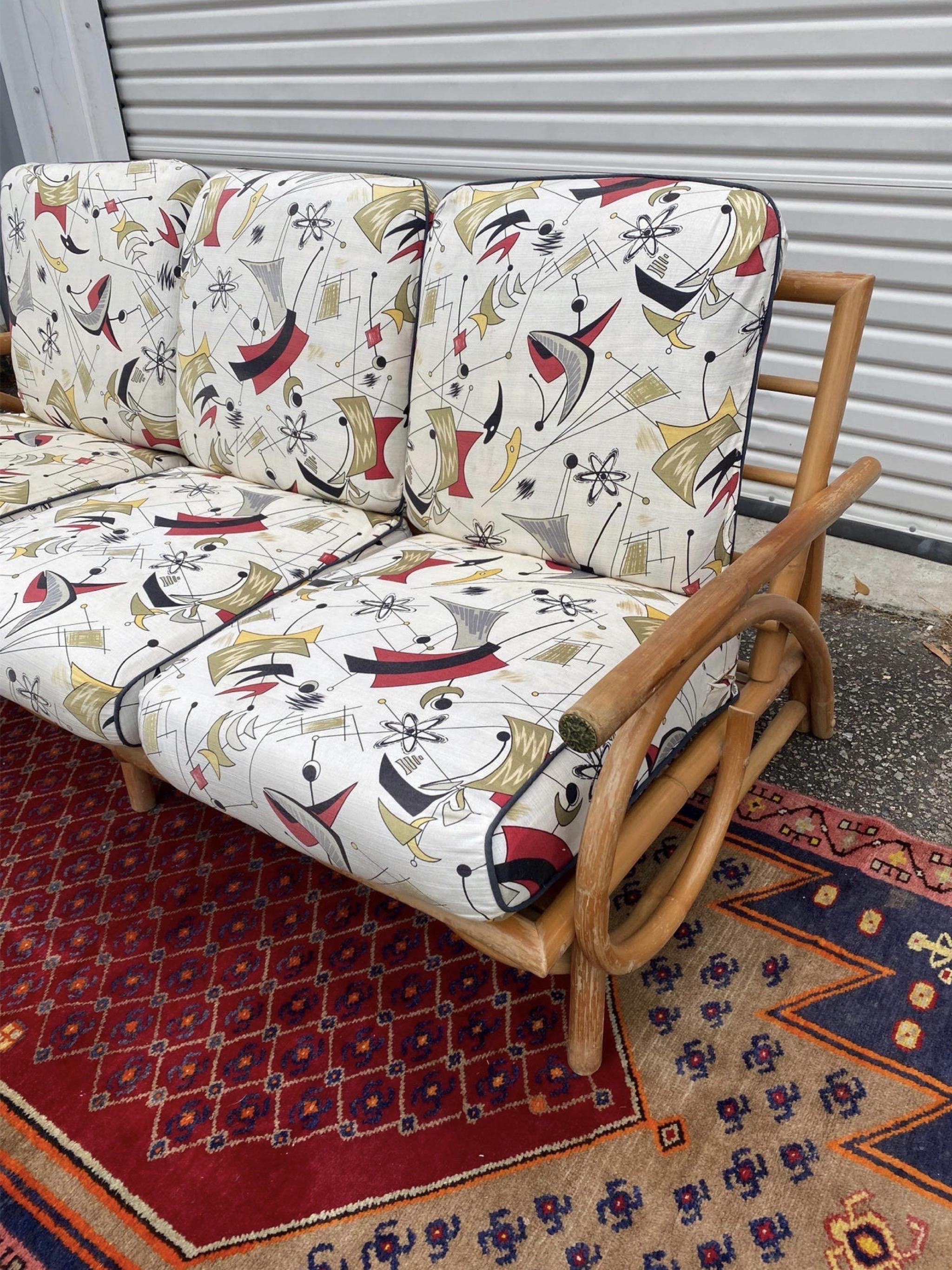 This stunning French bamboo sofa is so so comfortable!   New cushions slip covers have been redone in new old stock atomic barkcloth.   The arms have metal caps on the ends and the lines on the sofa are just wonderful with their swirls.  