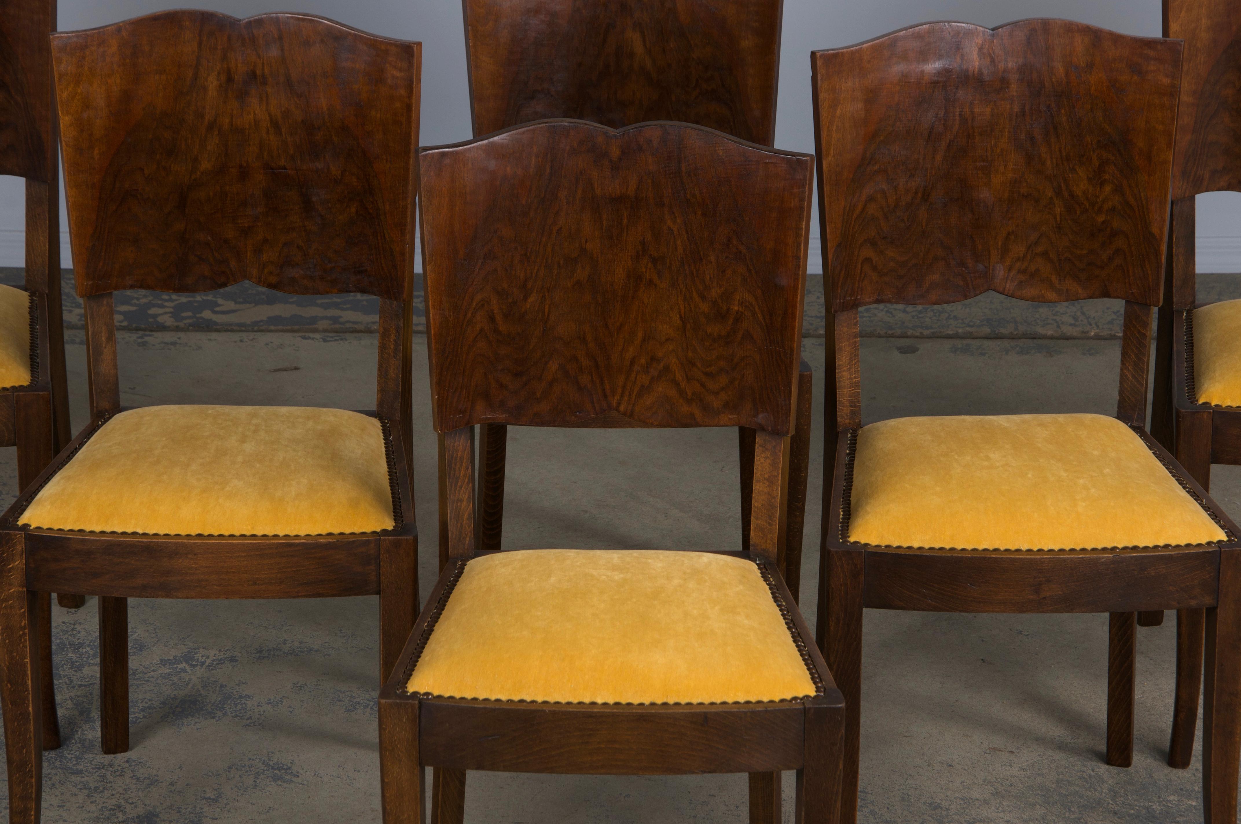 A stunning set of six 1950s French Art Deco dining chairs, sourced directly from Provence, France. Expertly hand-crafted from solid maple wood, these chairs feature a petite profile and a distinctive mustache-shaped backrest, adorned with a striking
