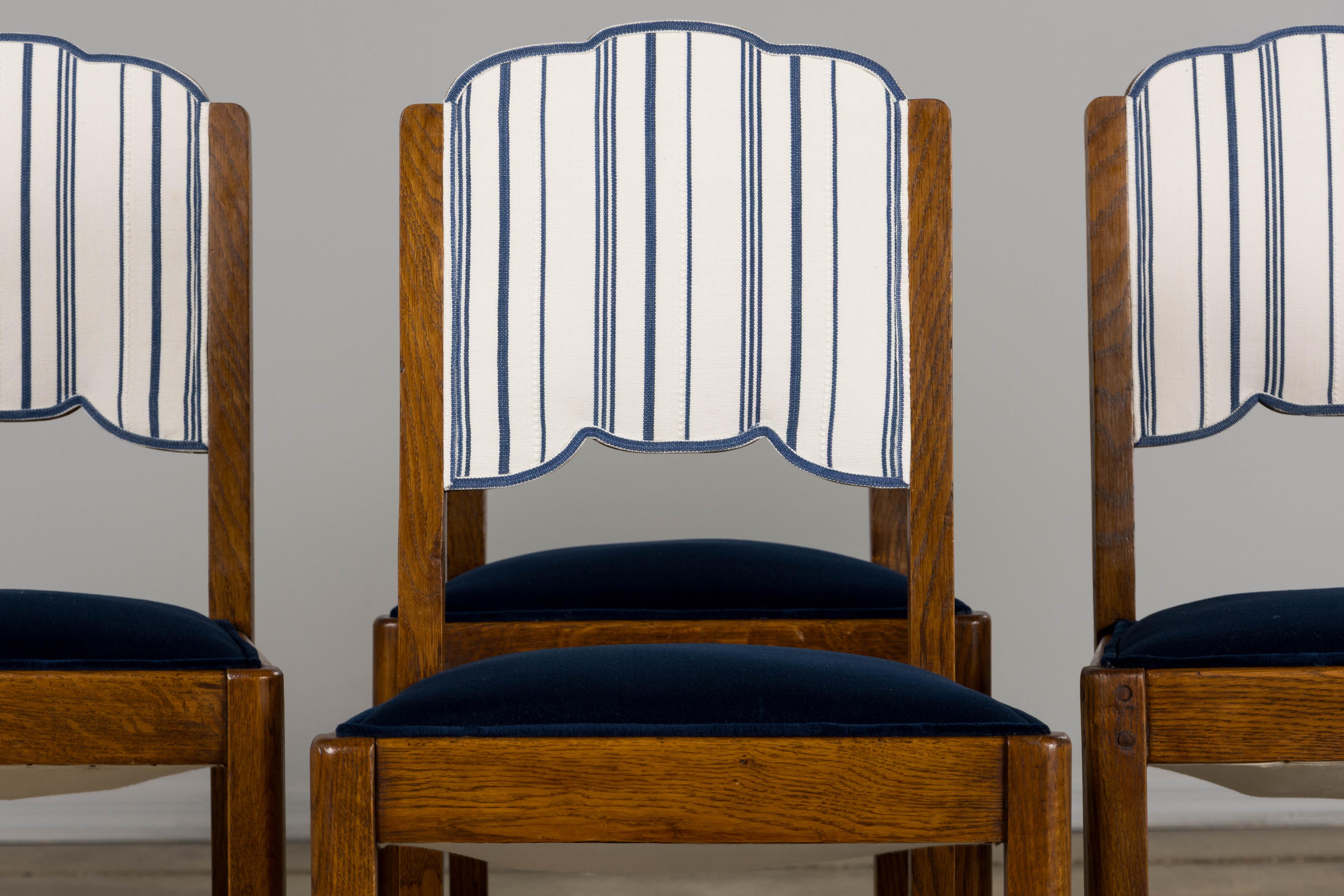 An elegant restored set of six 1950s French Art Deco dining chairs, sourced from Provence. Expertly crafted from solid oak, each chair features a petite profile with gracefully hand-carved scalloped backs, offering a refined and understated