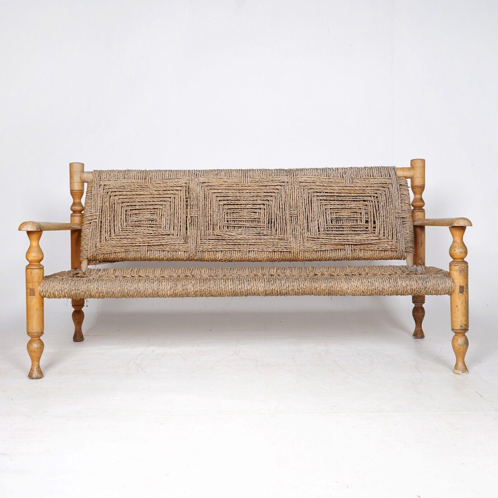 A 1950s rope bench in the style of French furniture designers Adrian & Frida Audoux-Minet. 
The bench features turned beech wood frame and original hand woven abaca rope seats and backs. 
The condition is fair, rope seat and back perfect. The front