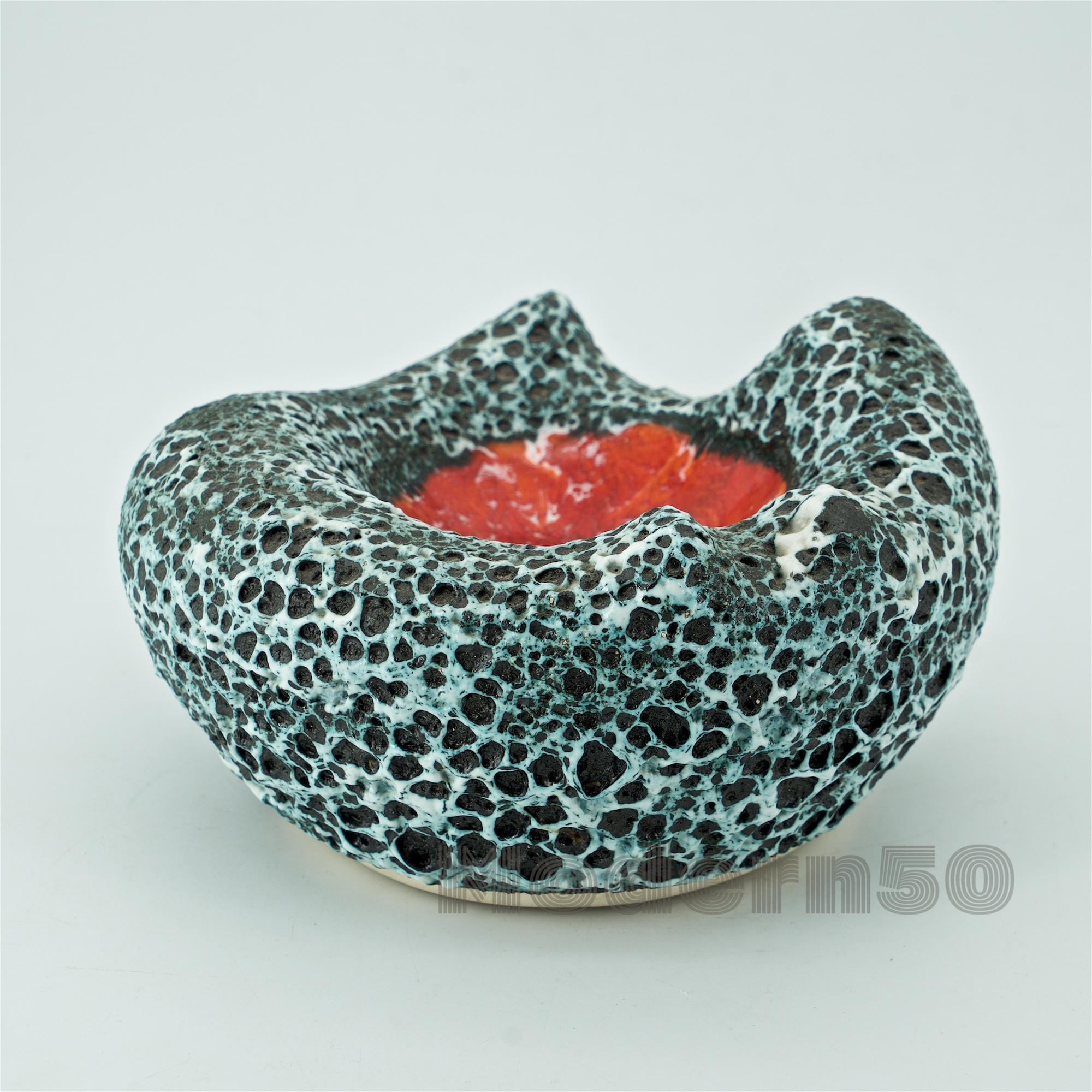 An organic form with volcanic lava black and white glaze and a high-gloss red center.
             