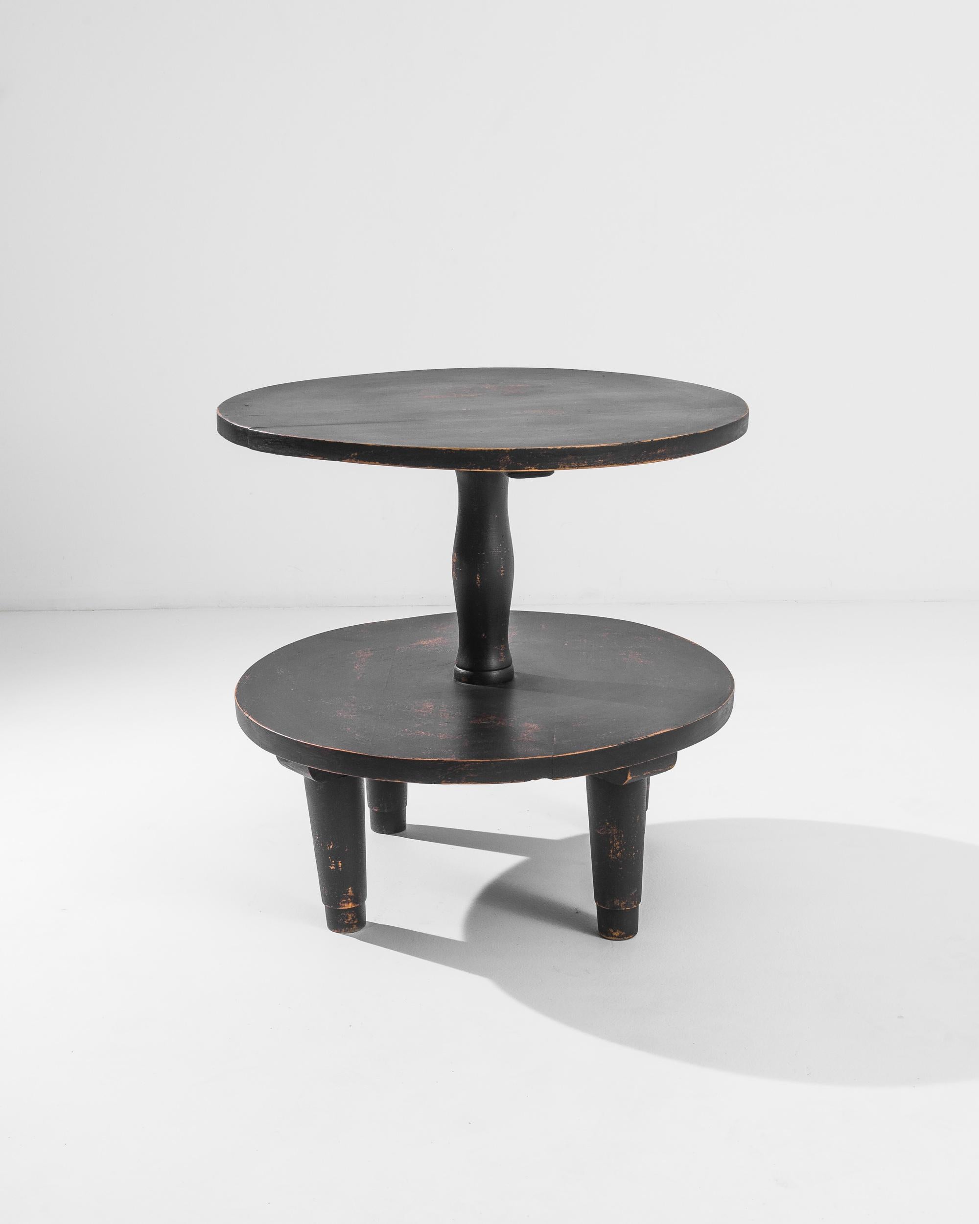 A vintage side table produced in France circa 1950, offering a beautifully distressed patina and a two-tier design. Standing on four stout tapered feet, this ergonomic piece rises above a modest twenty-four inches and is assembled around an