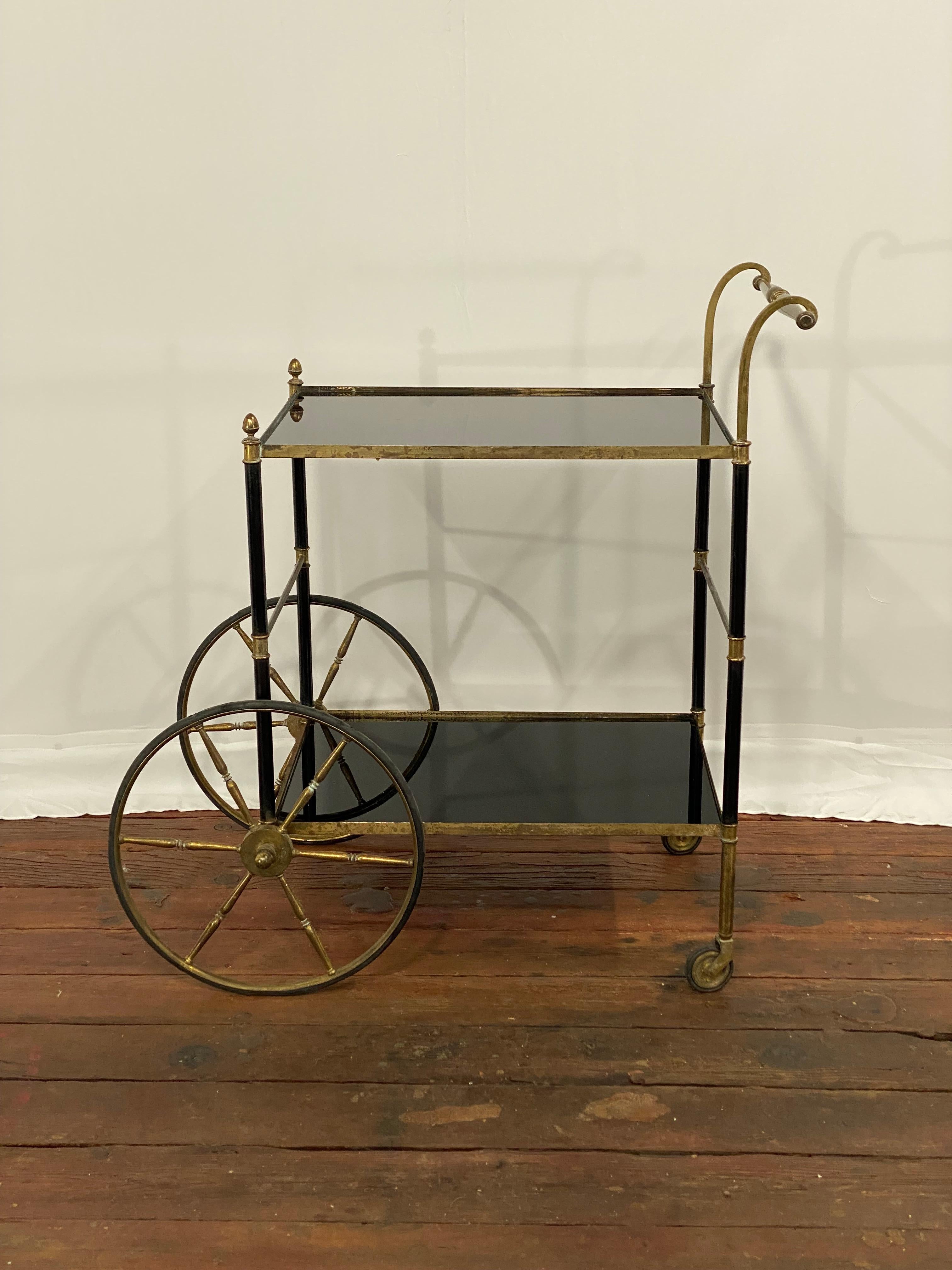 French brass and vitrolite black glass trolley cart. Beautiful, classy and refined. Circa 1950-1960. Featuring acorn finials, a scrolled handle and the original thick black glass. Imported be a California based interior decorator. 

Good overall
