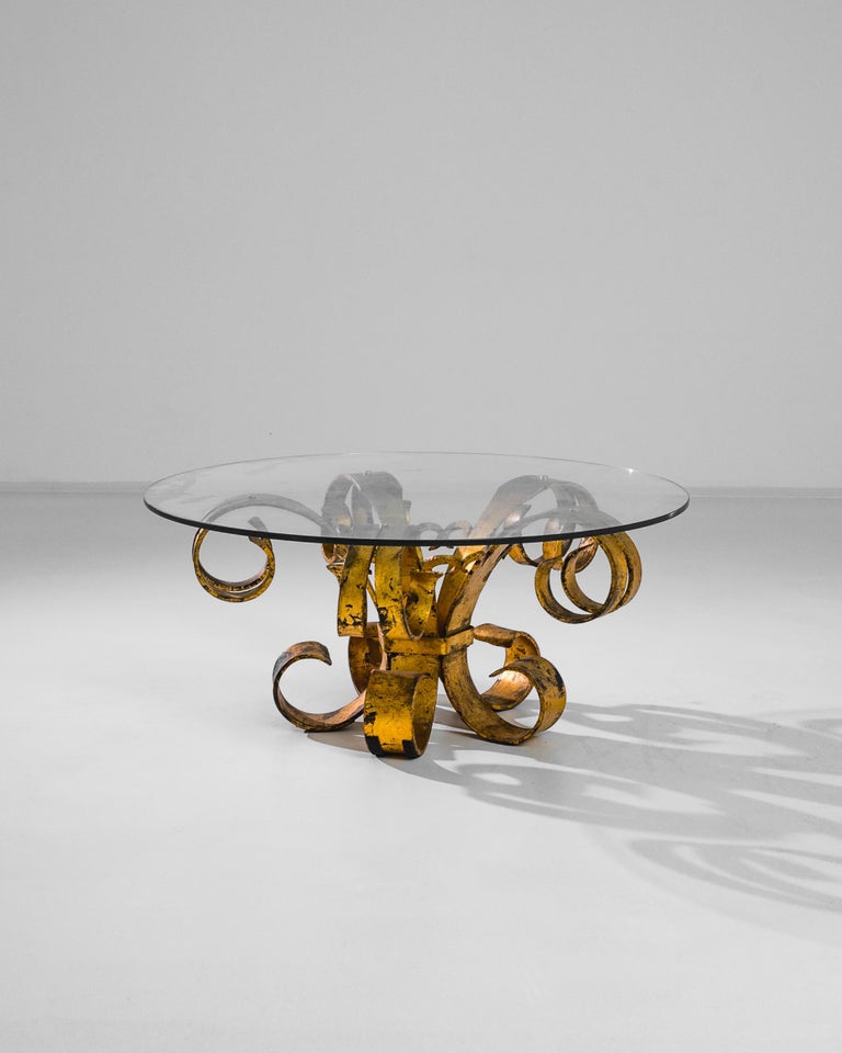 A show-stopping coffee table from 1950s France. An arrangement of flamboyant brass scrolls supports a circular glass tabletop — rococo maximalism with a clean, minimalist counterpoint. The gilded finish of the brass has aged to a striking patina,