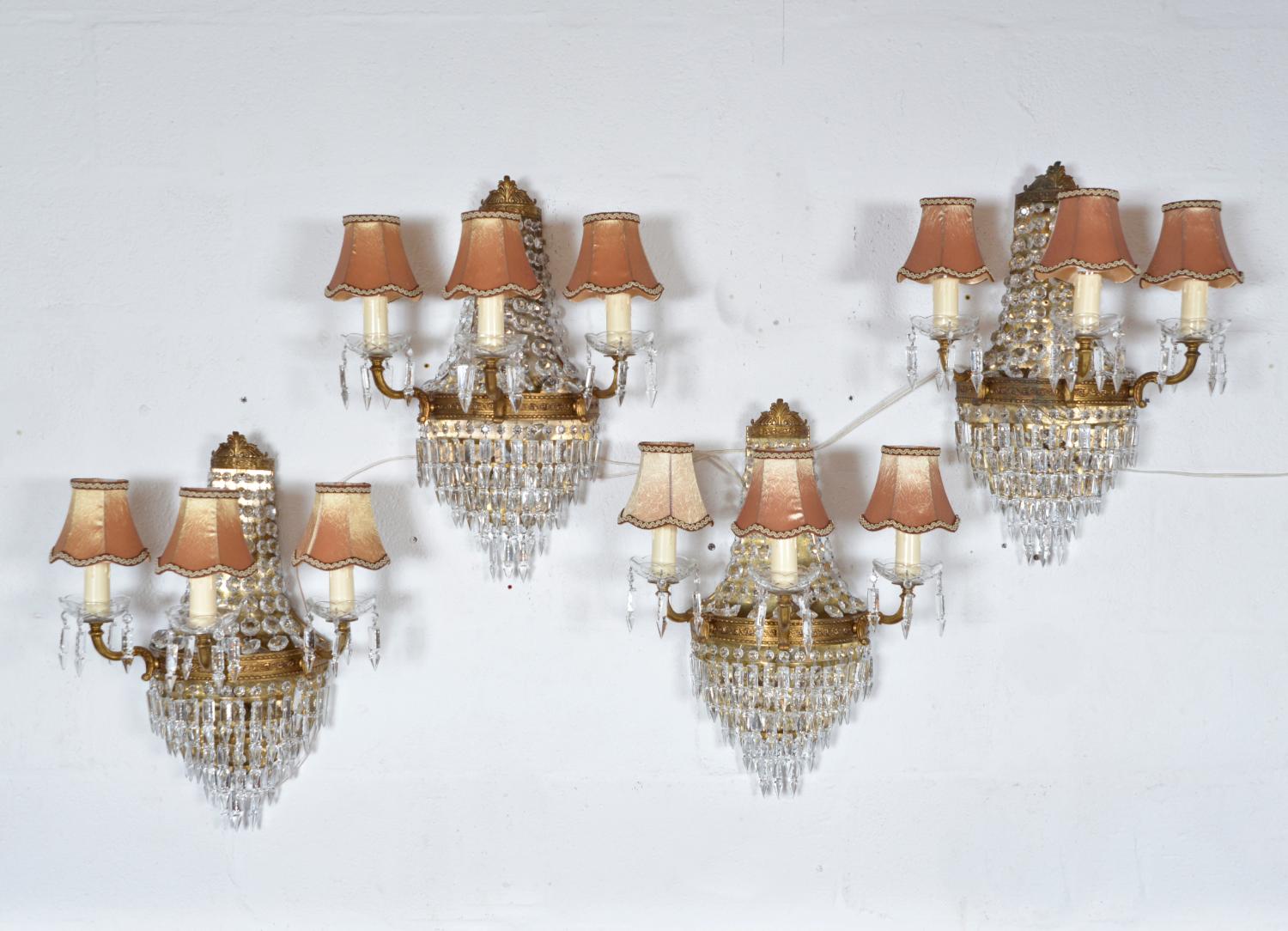A substantial set of four stunning French wall mounted chandeliers with generous strings of cut crystal prisms and multi faceted octagon crystal beads.
Each chandelier sconce has three gilt brass arms, each with a cut glass candle cup from which