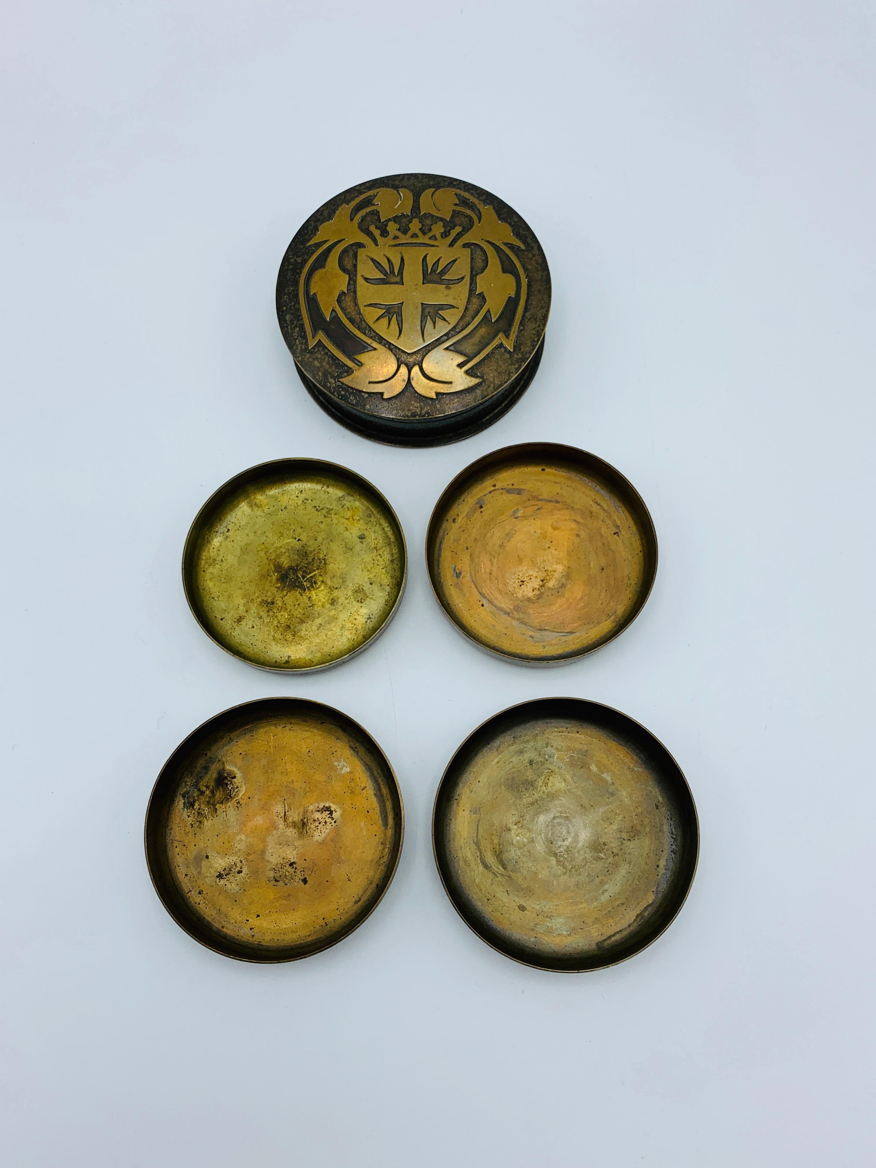 Listed is a fabulous, set of 4, 1950s French brass coasters. The set of coasters (slightly varying in diameter) nest into one another, to sit in the brass box with a shielded crest on the lid. Coasters measure 0.63