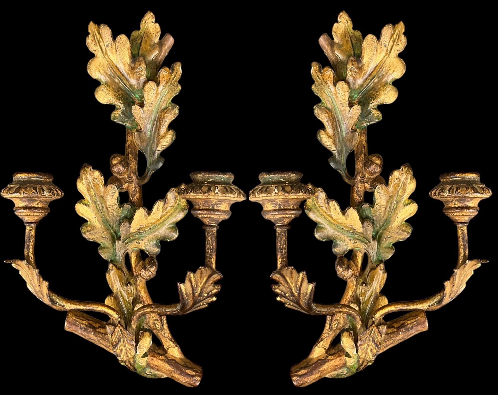 This is a pair of carved giltwood French sconces that depict spiraling leaves with branches and acorns. They most likely date to the 1950s. The pair is not electrified. 