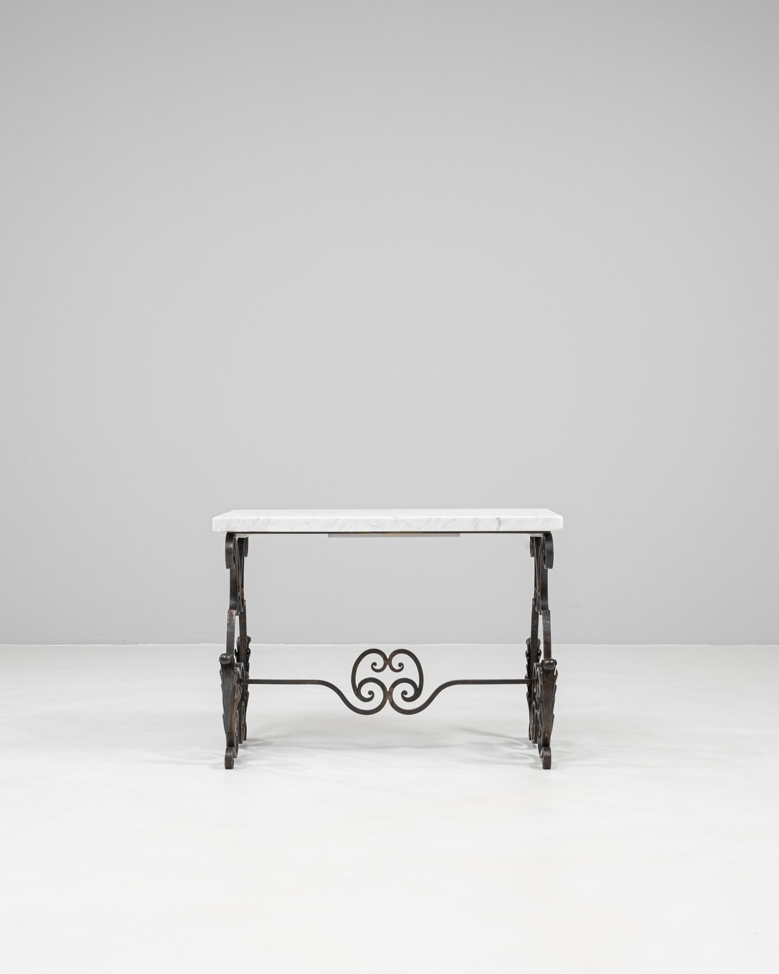This 1950s French side table features an elegant cast iron base with intricate scrollwork and a refined sense of symmetry. The hand-forged iron displays a dark patina that beautifully contrasts with the polished white marble top, creating a timeless