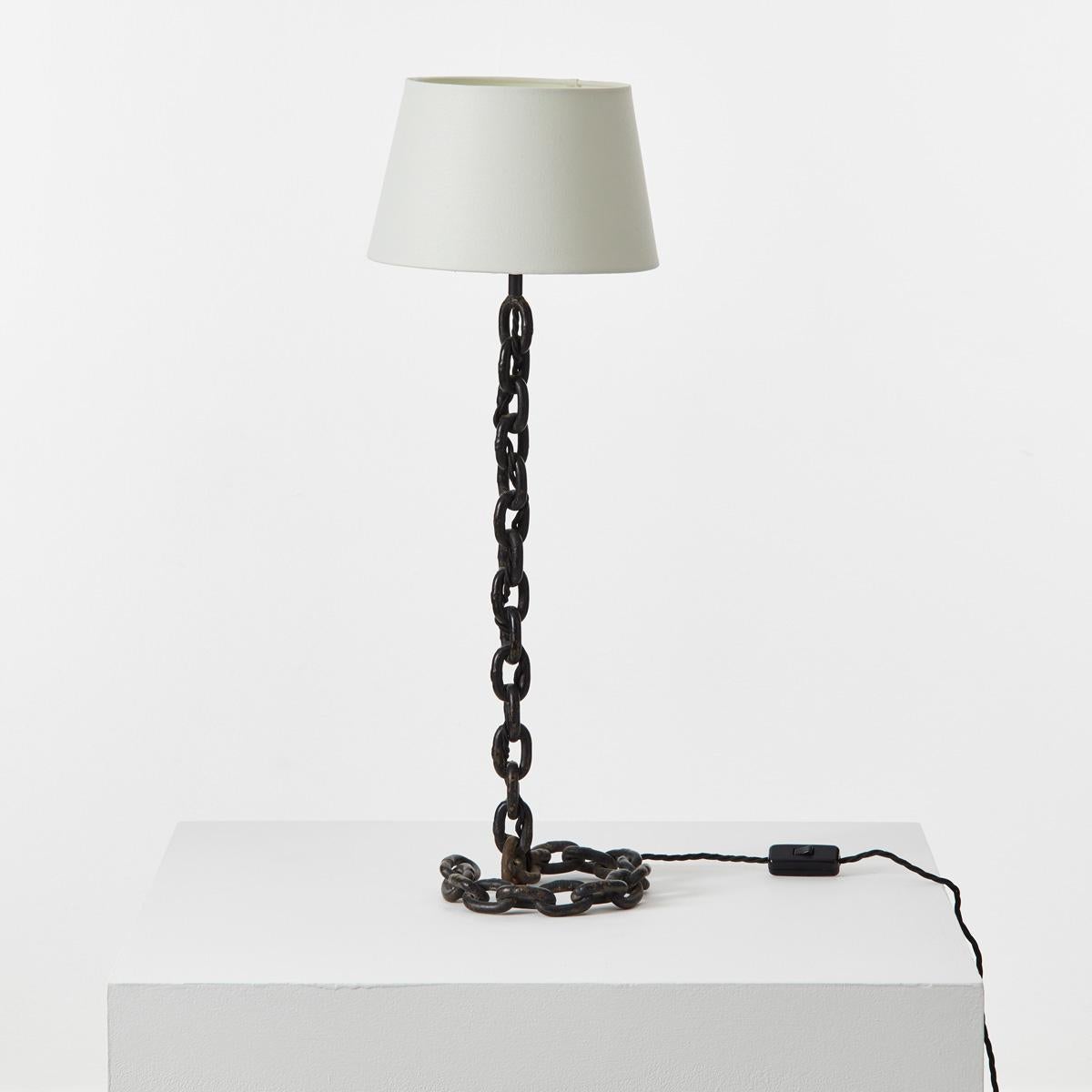 An unconventional table lamp in the manner of artist Franz West. Seemingly defying gravity, its welded iron stem drapes and curls into a circular base. Playful and elegant in equal measure.
 