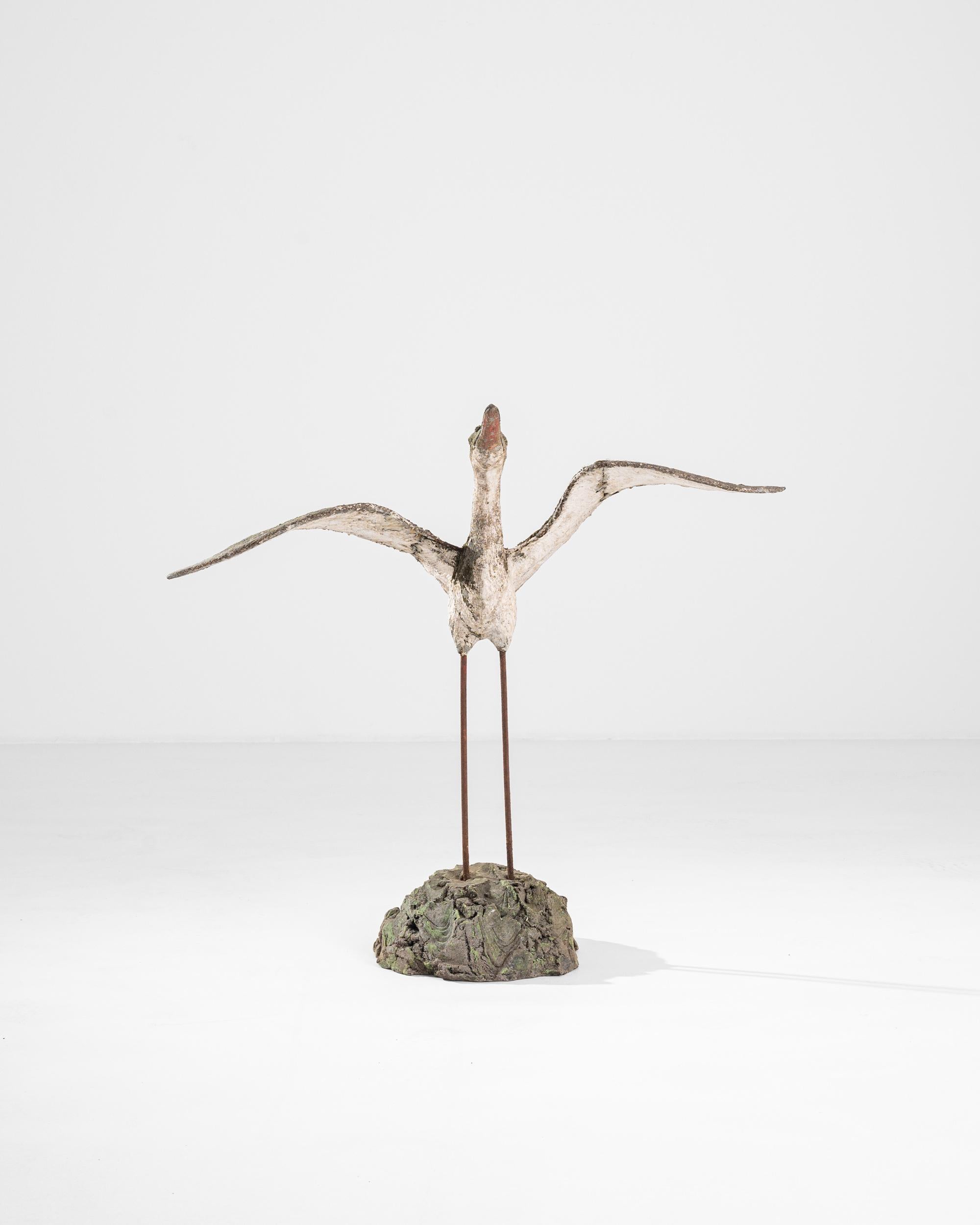 This vintage concrete sculpture depicts a heron, captured in the moment, about to take flight — neck extended, beak lifted, wings raised. Made in France in the 1950s, the weathered finish of the concrete gives this piece a unique appeal. The colors