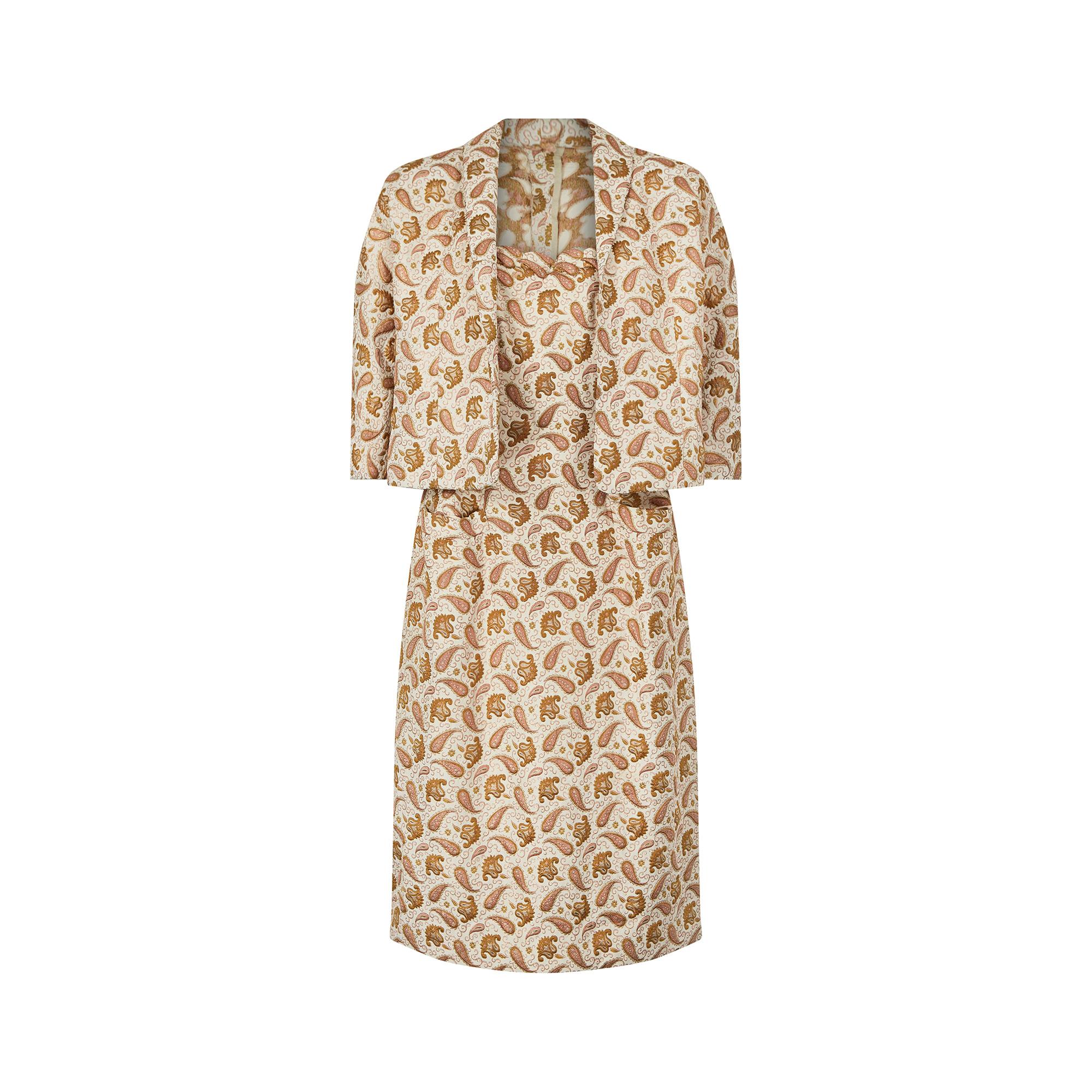 Cet ensemble de robe couture deux pièces en brocart de soie des années 1950 présente un étonnant motif cachemire en fils roses et dorés. La robe présente une bordure festonnée sur le haut du corsage et trois séries de pinces descendant du buste pour