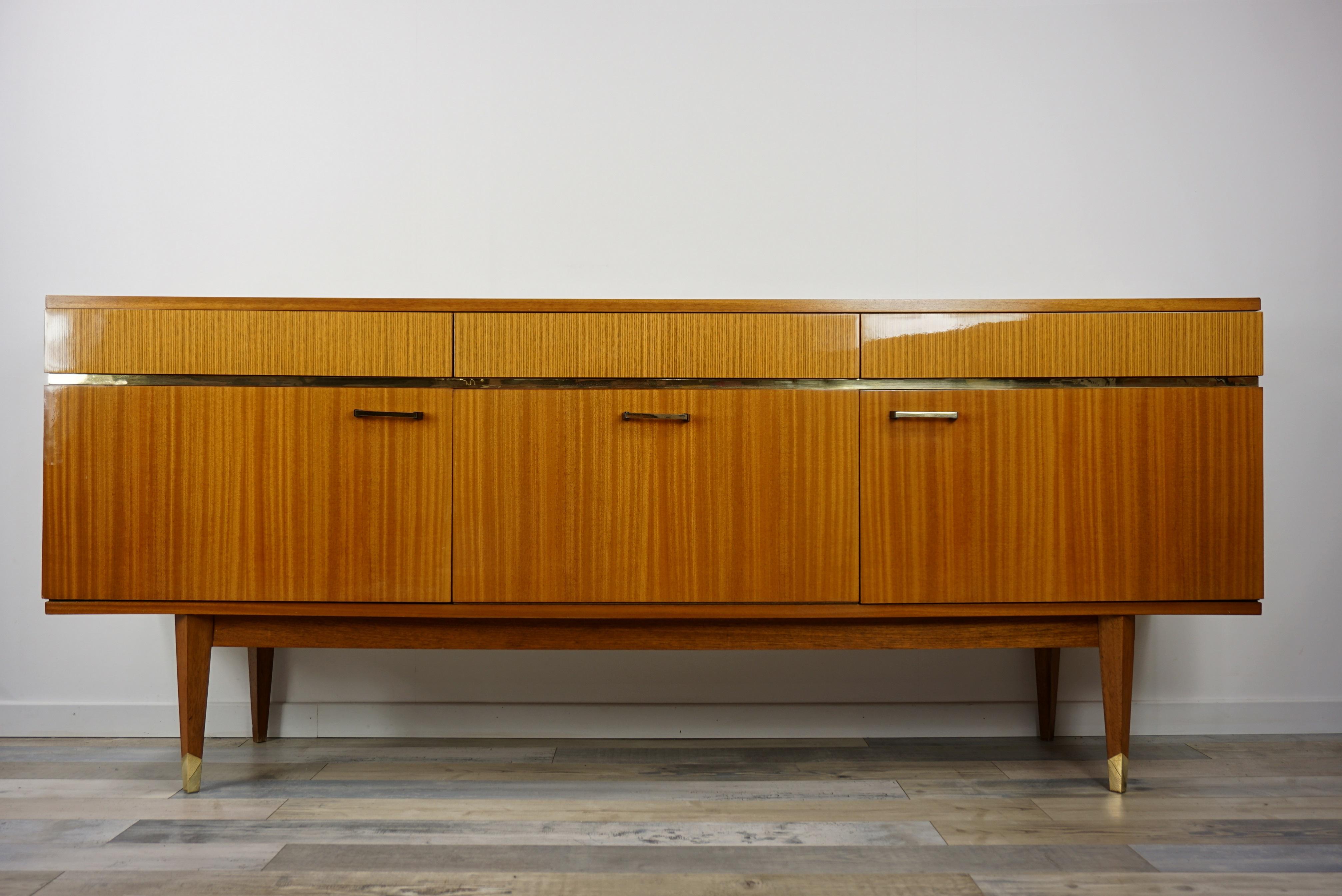1950s French design wooden and glossy sideboard with pure and harmonious lines. Composed of a wooden structure, compass feet with brass finish, 3 drawers (invisible sculpted handles) and 3 closed storage spaces; shelves on each side and a dry bar