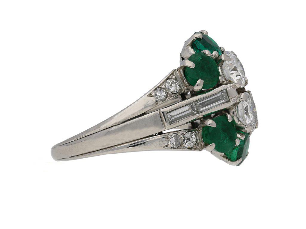 Vintage diamond and emerald cluster ring. Set vertically with two round old cut diamonds in open back four claw settings with a combined weight of 0.60 carats, surrounded by six round brilliant cut natural emeralds with no colour enhancement in open