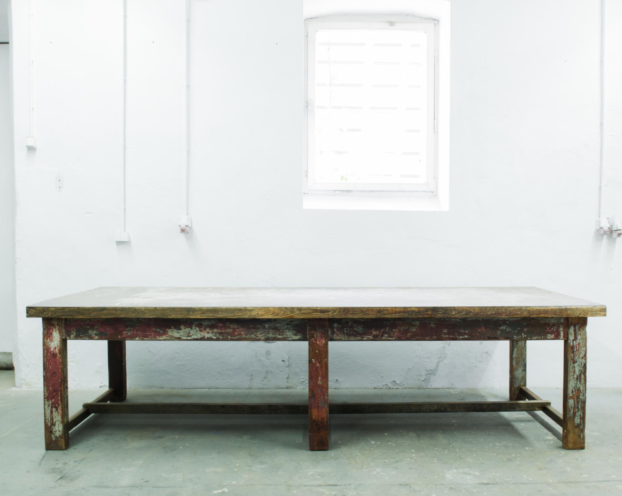 A wood patinated table from France, produced circa 1950. A long—nearly ten feet—, six legged, work table with layers of original patination. A functional piece that is beautiful for its sturdiness and durability as much as its aesthetic