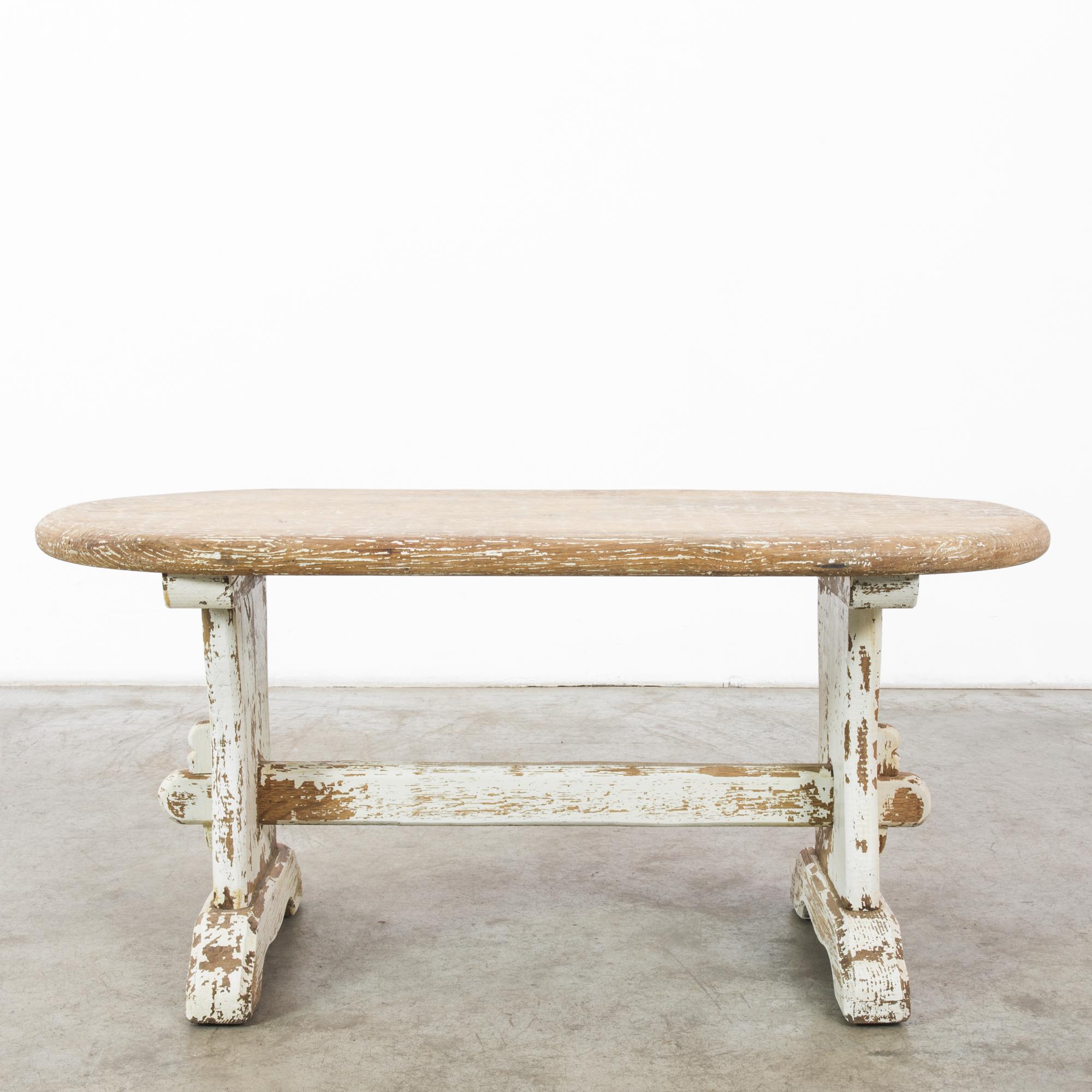 This wooden trestle table was made in France, circa 1950. The solid posts and traditional joinery impart a charming, handcrafted quality and a medieval spirit. It evokes the warmth of a rustic farmhouse with the distressed white frame and earthy