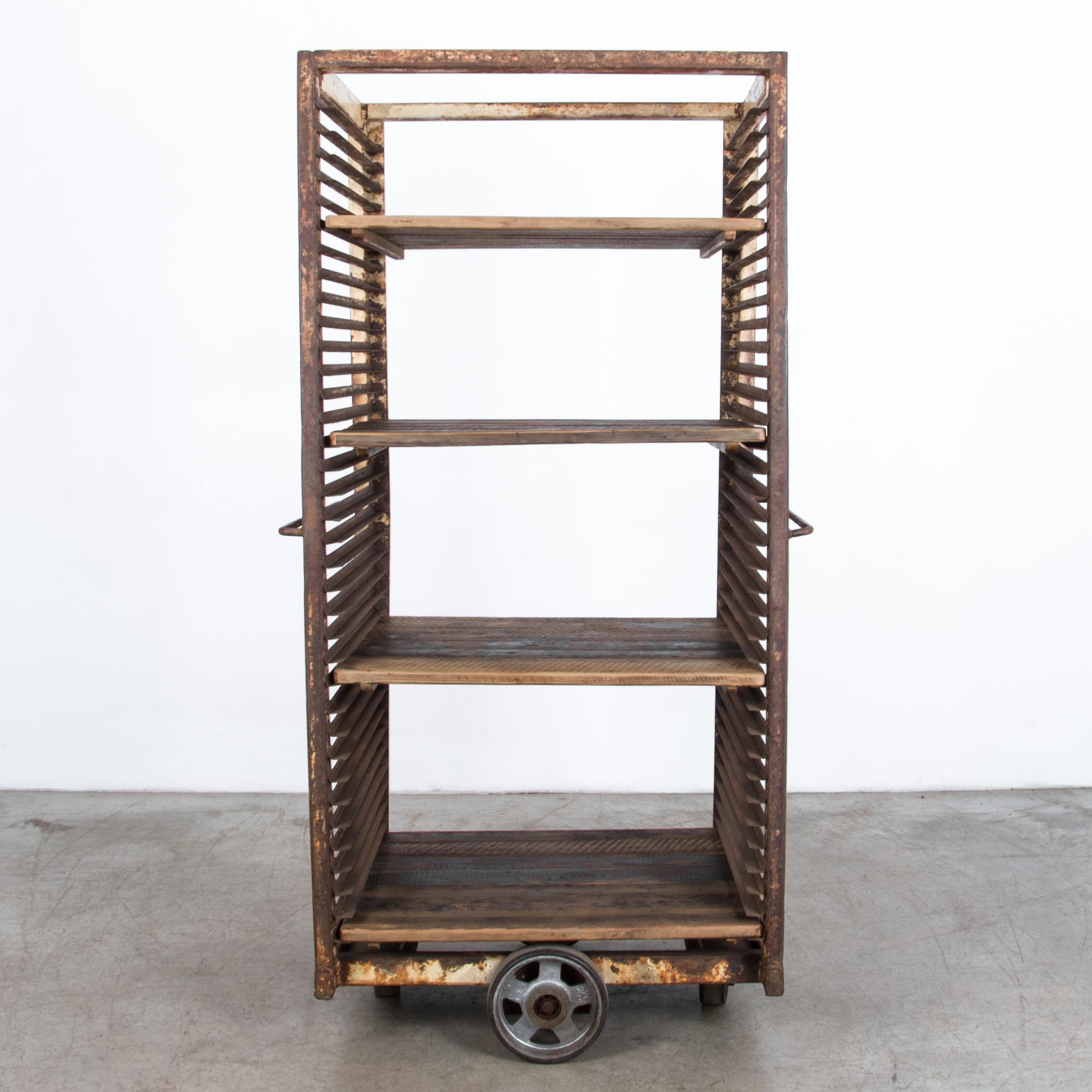 From France circa 1950, a tall wheeled iron cart with adjustable wooden shelves. With a thick textured patina worn by years of use, this shelving unit brings an industrial touch to a space needing texture.

A selection is available in a range of
