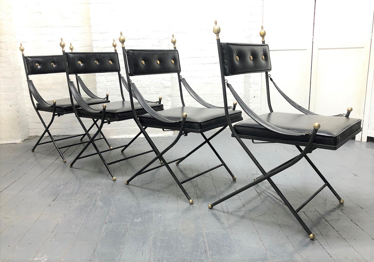 1950s French iron and brass dining chairs. The chairs have iron frames, are black vinyl, with brass finials to the top and brass ball feet. The chairs also have sloping arms and fold for easy storage.  Can be used indoor or outdoor chairs.
