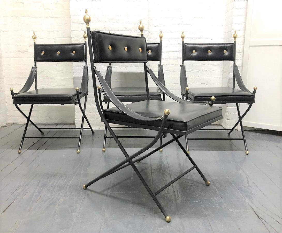 1950s French iron and brass dining table and chairs. The set has iron frames, chairs are black vinyl, with brass finials to the top and brass ball feet. The chairs also have sloping arms and fold for easy storage. The table has a smoked glass top.