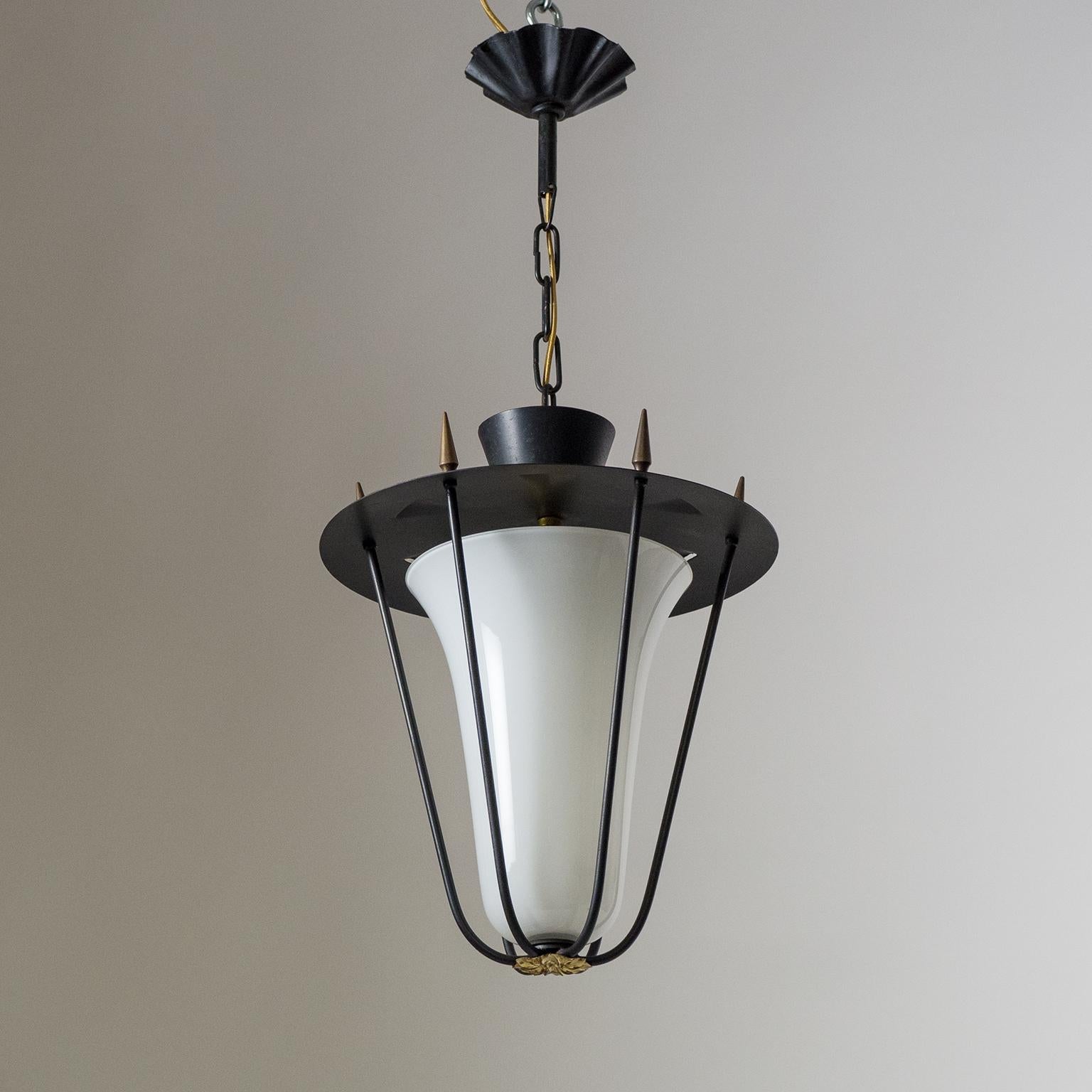 French modern lantern from the 1950s. Black lacquered hardware with a rare tapered tulip-shaped cased glass diffuser. Six spike-shaped brass knobs attach the cage body to the shade on top and a brass floral finial on the bottom provides a nice