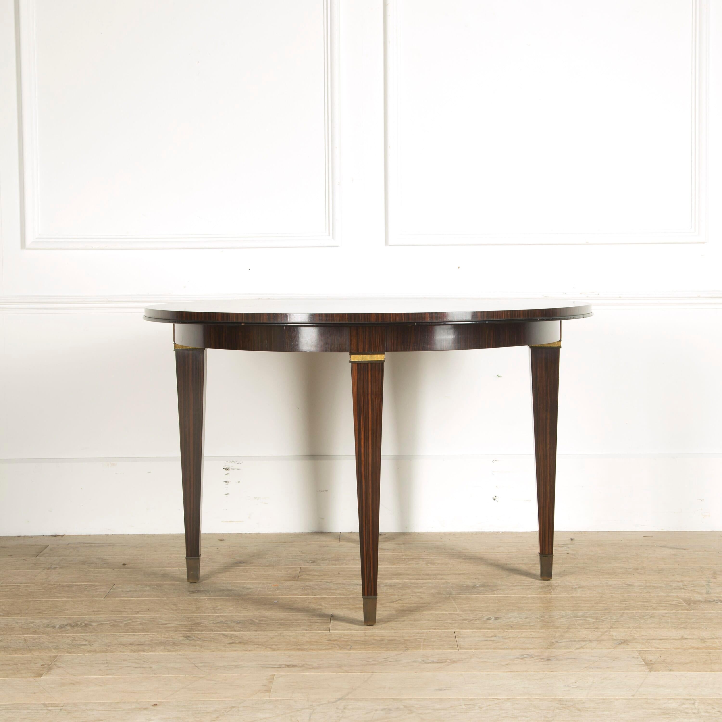 A fine quality and very chic 1950s French centre table, the top radially veneered in Macassar Ebony, the legs veneered in Macassar ebony and terminating in large brass sabots.