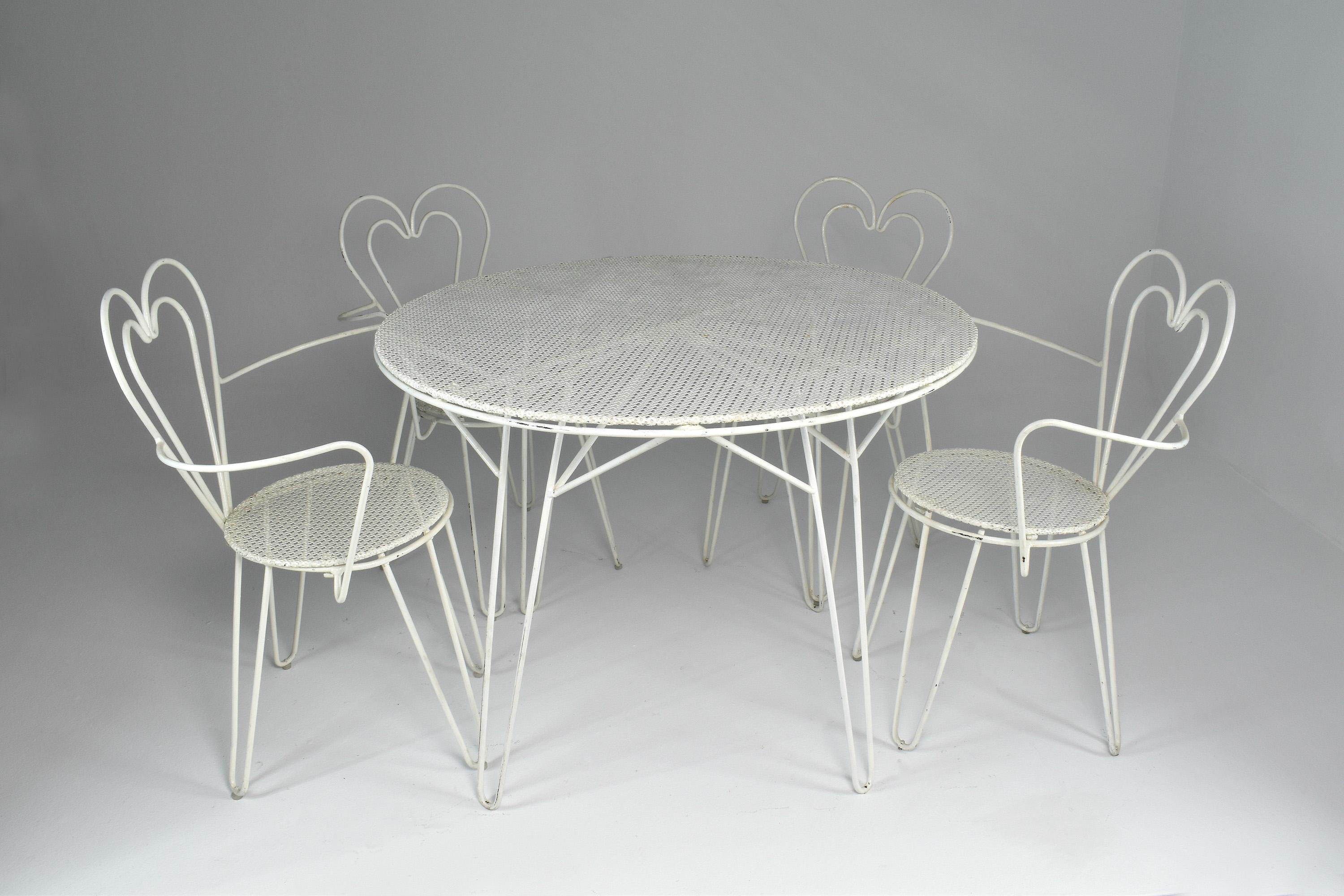 A beautiful assemble attributed to the iconic French mid-century designer Mathieu Mategot composed of a circular garden table and four heart-shaped chairs. These collectible pieces are made of his signature perforated sheet and white tubular