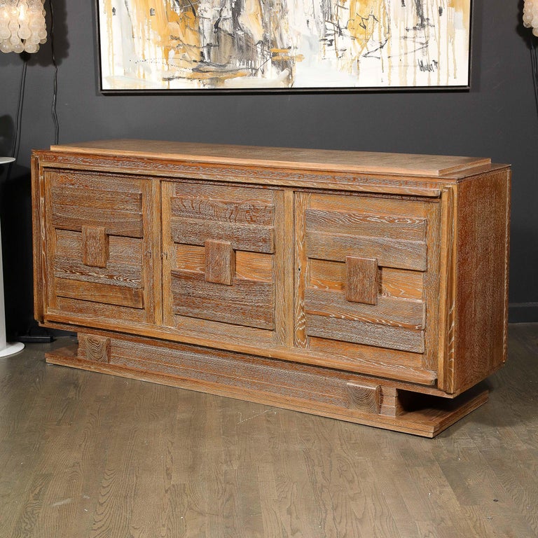This stunning Mid-Century Modern cabinet was realized in France circa 1950. Offering a stunning limed finish- that brilliantly highlights the inherent wood oak grain with white pigmentation- the piece sits on a plinth base consisting of stacked