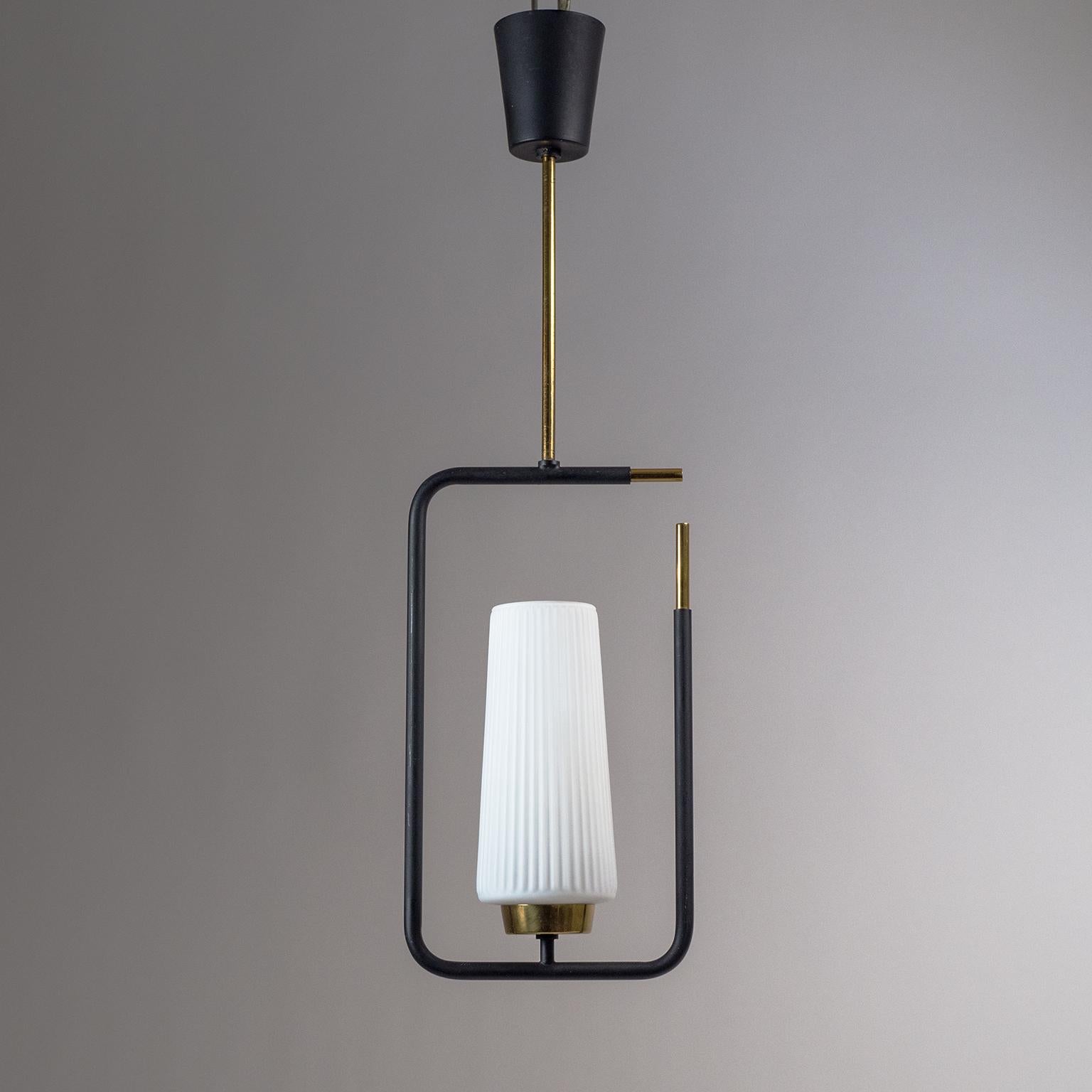 Modernist French pendant from the 1950s. A slightly conical ribbed glass diffuser is framed by a black lacquered structure with brass details. The glass diffuser has a white casing on the inside and a satin finish. One brass and ceramic E14 socket