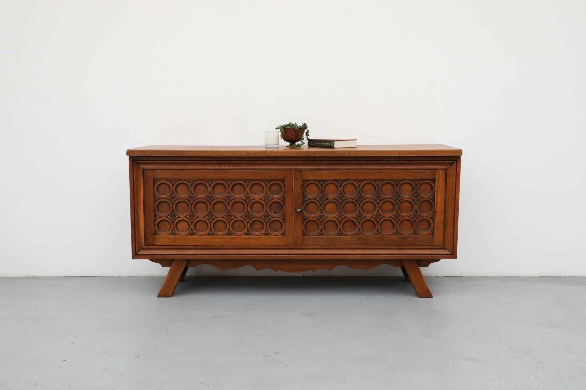 Questa credenza francese in Oak Oak, risalente agli anni '50, incarna l'eleganza rustica e la maestria artigianale tipica dello stile di Charles Dudouyt. Realizzato in rovere pesante e robusto, riflette il fascino duraturo del design modernista