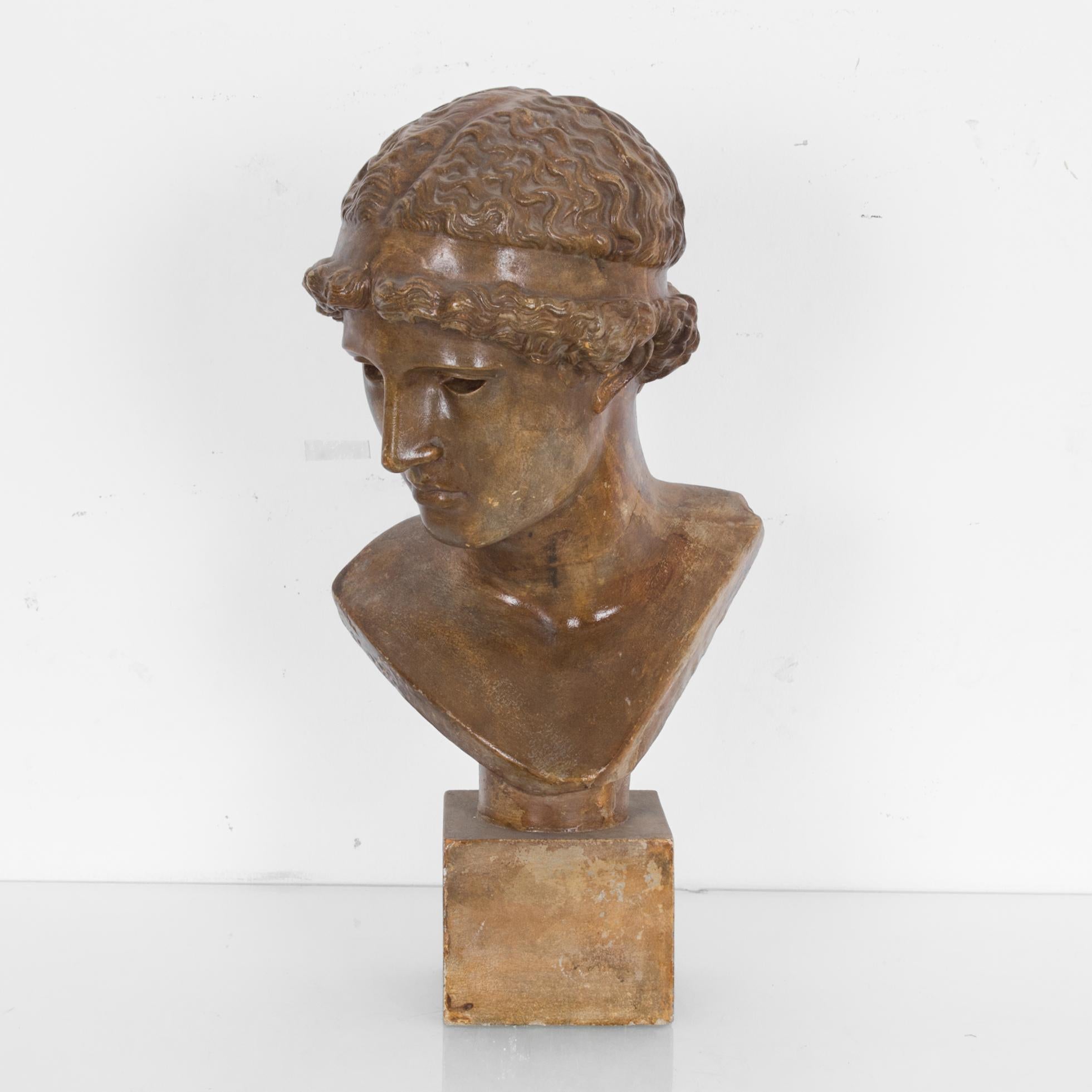 A sculpted bronze colored bust produced in France, circa 1950. References Classical Greek and neoclassical statues, like Kritios Boy and Donatello’s David. The glossy finish, along with the simplified yet detailed features gives this piece an august
