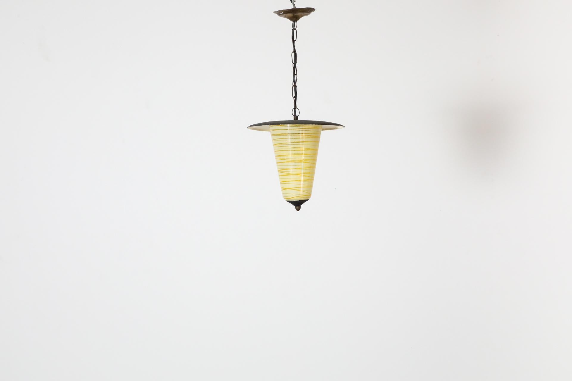 Piano in metallo smaltato nero con paralume in vetro giallo a cono con strisce giallo pallido e minuteria in ottone. In condizioni originali, con un'usura visibile che corrisponde all'età e all'uso. Sono disponibili altre lampade simili, elencate