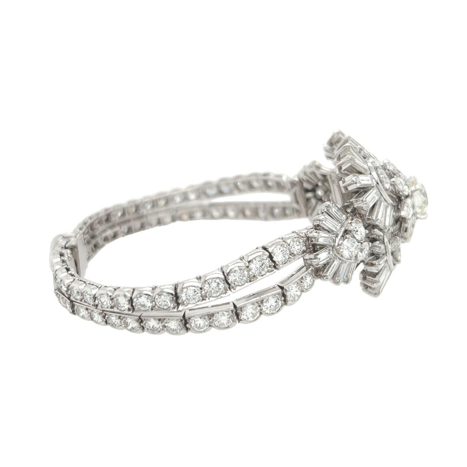 A platinum and diamond bracelet.  Circa 1950. French.  Designed as a baguette-cut diamond spray, centering an old European-cut diamond, enhanced by pear and round brilliant-cut diamonds, with a circular-cut diamond strap bracelet. Center diamond