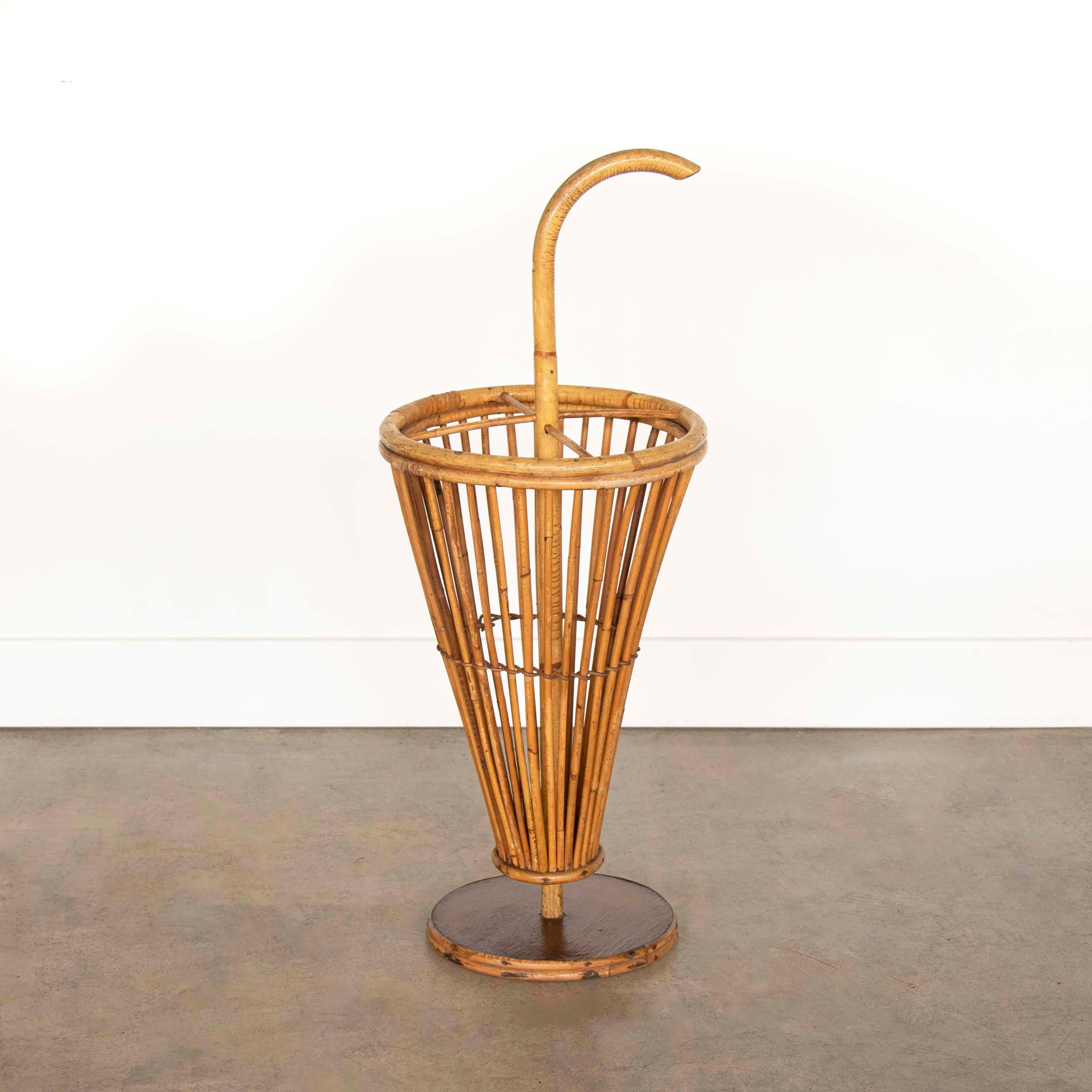 Great French rattan umbrella holder from the 1950s. Circular rattan and wood base with funnel shaped slatted rattan holder and curved handle. Unique vintage piece. Great natural coloring and patina.