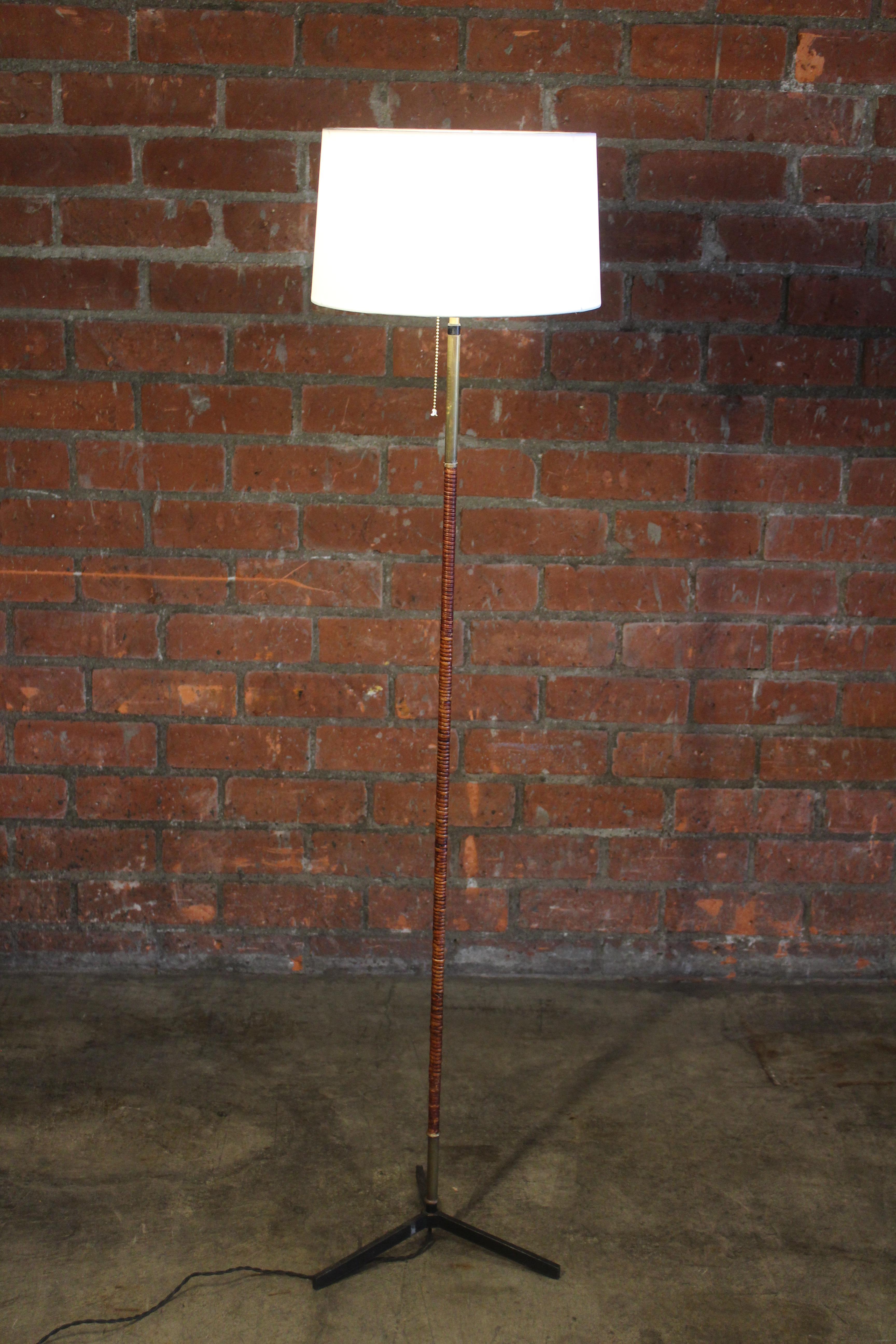 A vintage rattan wrapped floor lamp with a brass stem and iron base. Newly rewired with a silk shade- custom made.