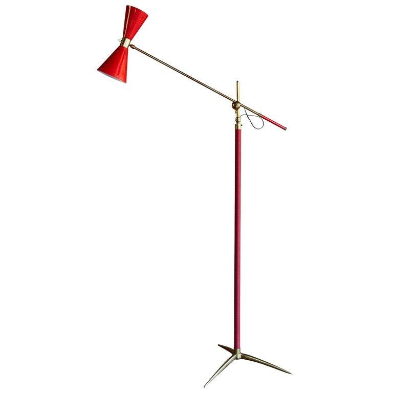 1950s French red articulating floor lamp. Executed in red painted metal, red vinyl and brass. An interesting amalgam of the styles of Arteluce, Kalmar and Lunel, this floor lamp is highly sculptural with its brass tripod base and elegant