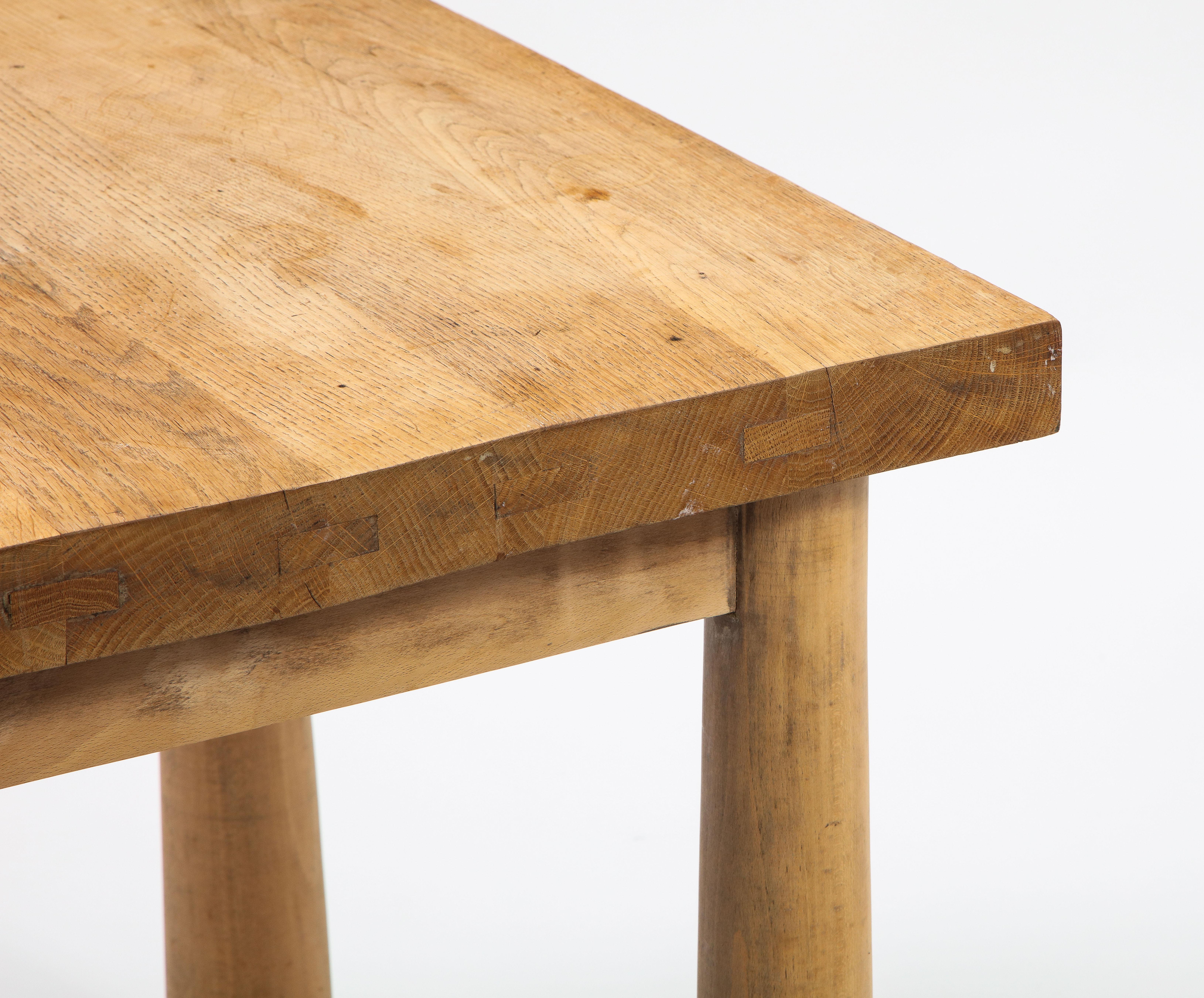 Midcentury square French table in oak, in the manner of Charlotte Perriand. The legs possess a slightly conical form and extend outwards toward the bottom. Wonderful patina.