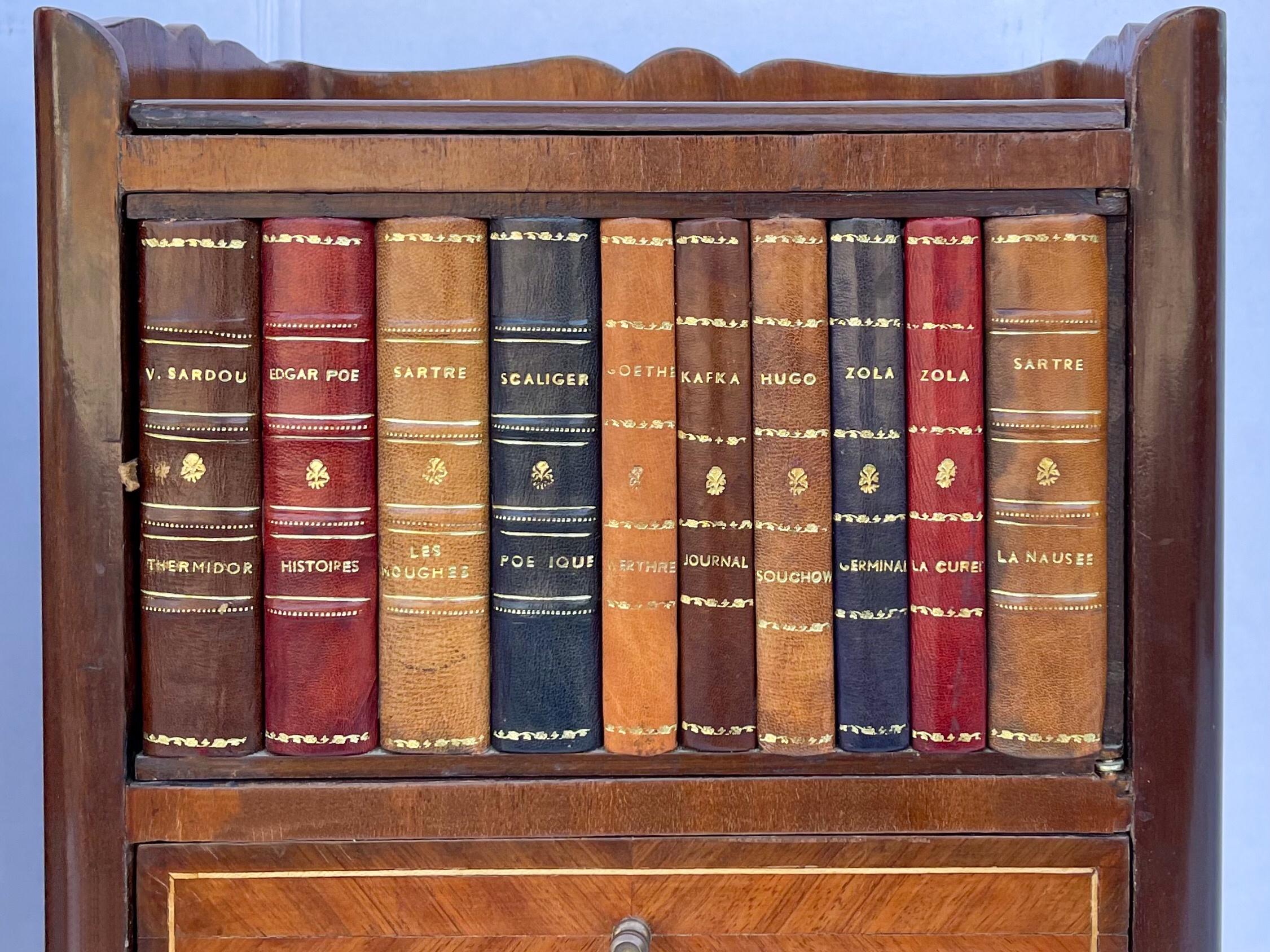 This is a pair of mahogany and satinwood inlaid faux book tables with French styling. The embossed leather book bindings depict the classics and open to hidden storage. They are unmarked and in very good condition.