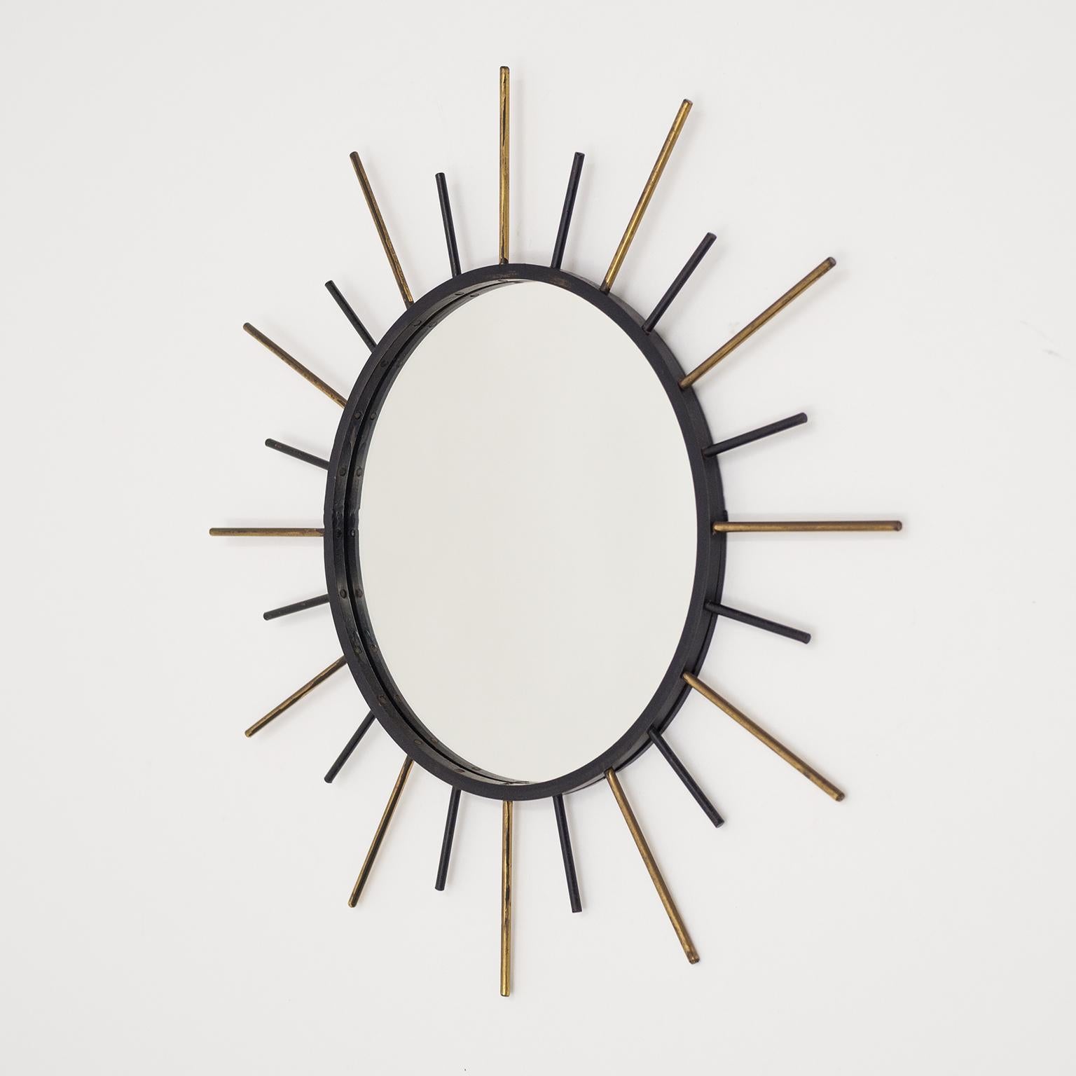 Französischer modernistischer Sonnenschliffspiegel aus den 1950er Jahren mit geschwärztem Stahlrahmen und abwechselnden Strahlen aus Messing und Stahl. Guter Originalzustand mit Patina auf dem Messing und einigen leichten Farbverlusten.