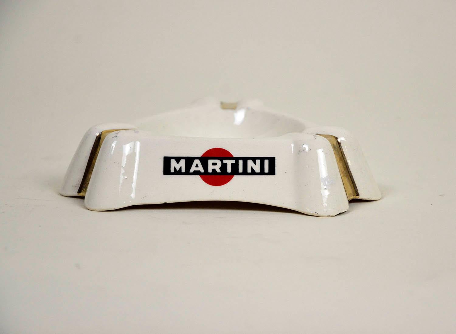 1950s French white triangular ashtray with gold details and Martini logo on all three sides, in demi porcellaine by Badonivillier France.

Collector's note:

Martini is a brand of Italian vermouth, named after the Martini & Rossi Distilleria