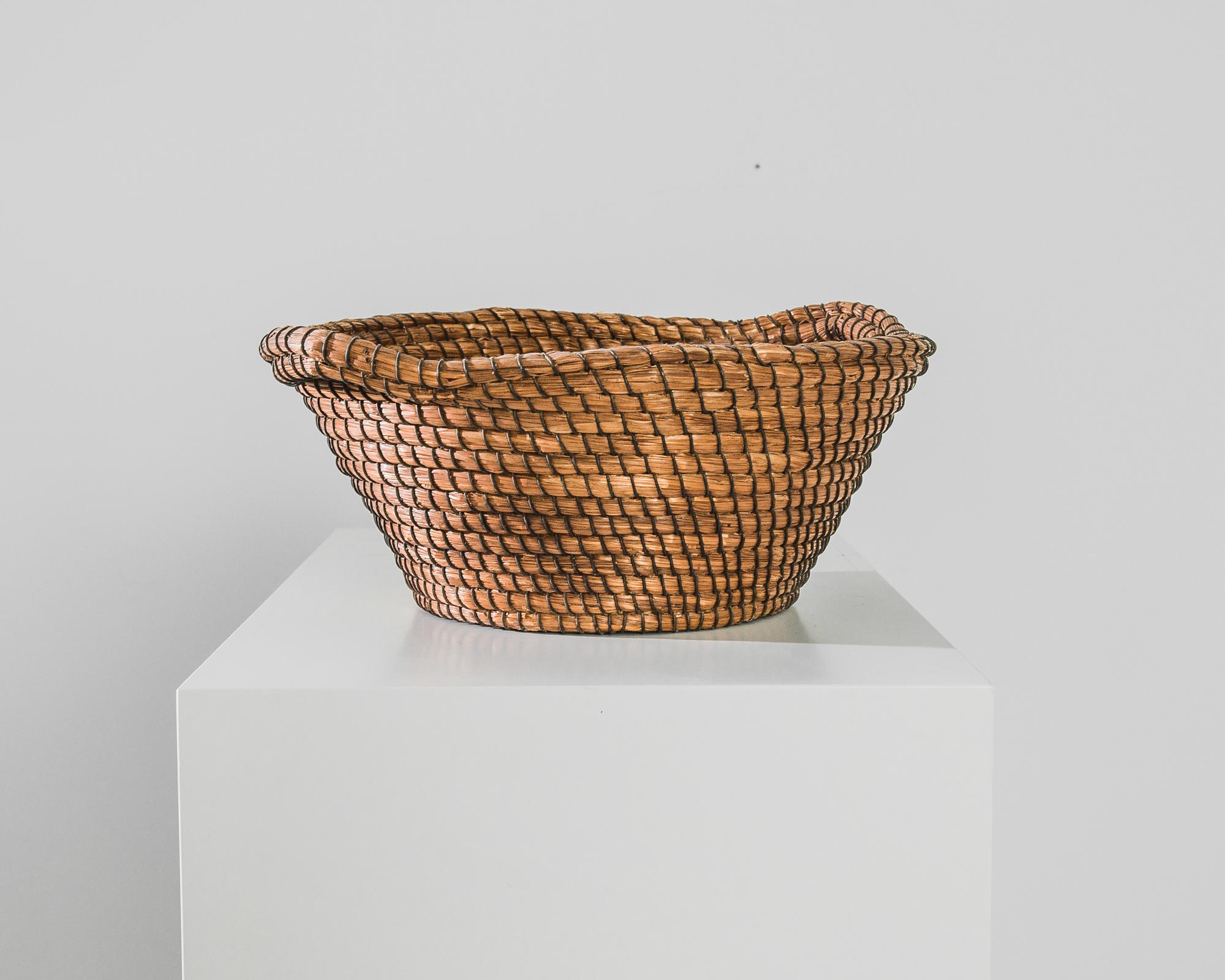 The oldest method of containing and collecting, the basketmaker's fond memories are woven into this charming find from France, circa 1950. This reed basket is constructed from natural fibers, held together by carefully curled metal wire; two handles